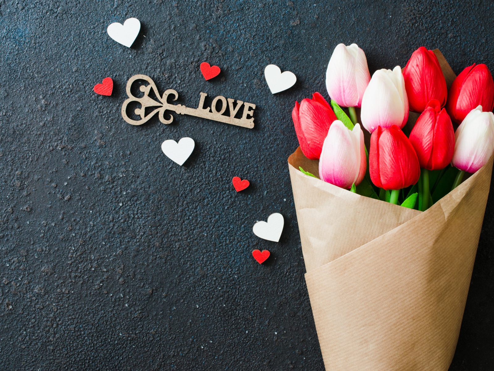 Букет тюльпанов в бумаге на черном фоне с ключом