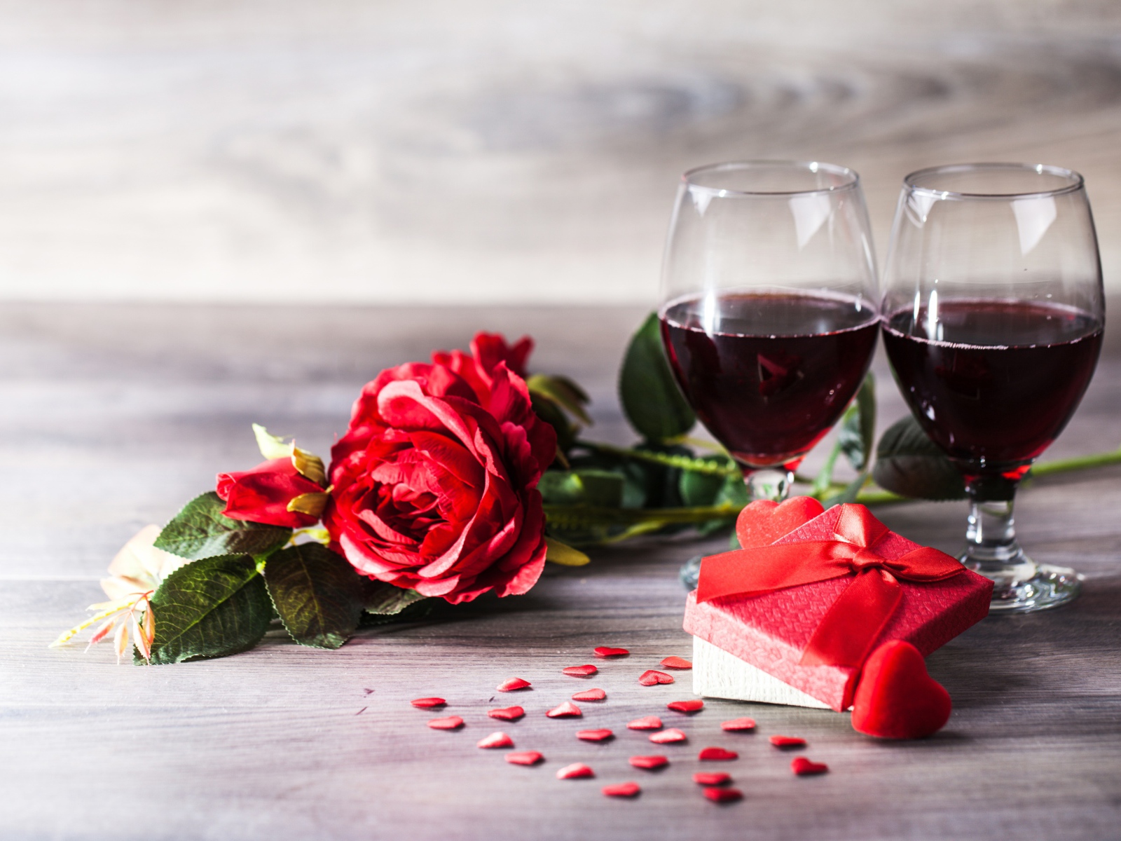 Розы, подарок и два бокала вина на столе