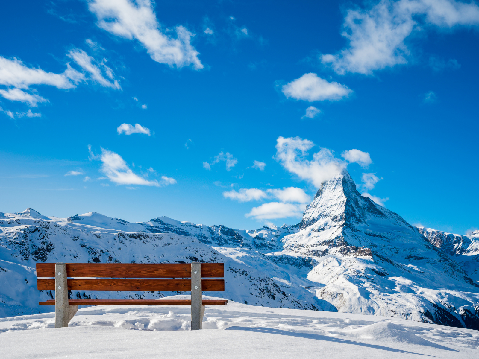 Bench in the snowy mountains under a blue clear sky
