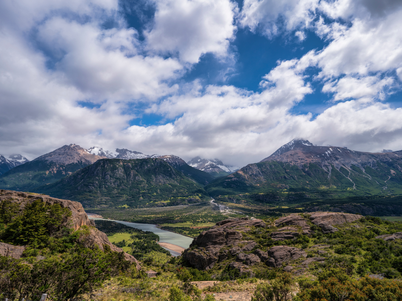 Белые облака в голубом небе над покрытыми зеленью горами