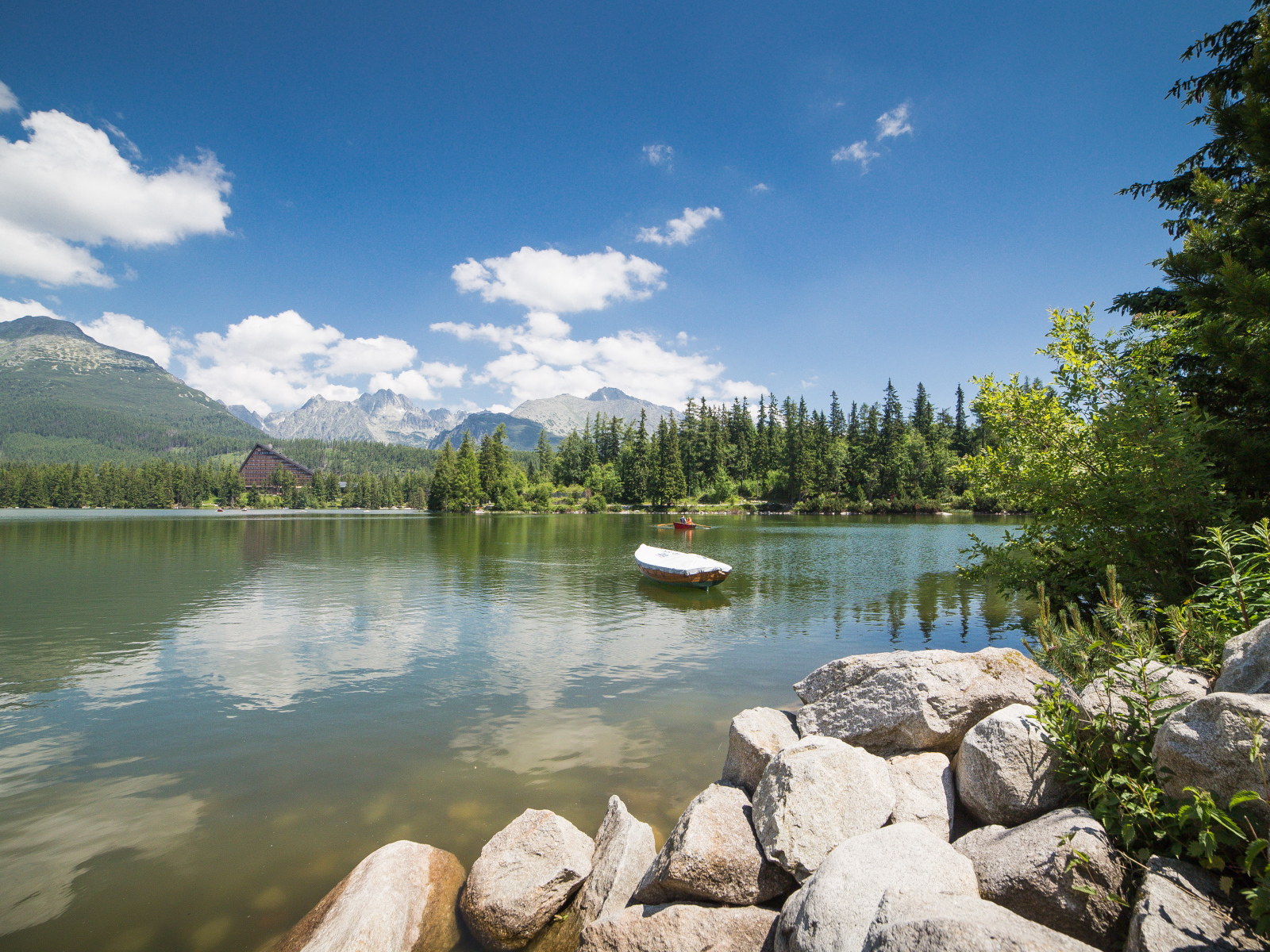 Лодка в озере на фоне гор под голубым небом