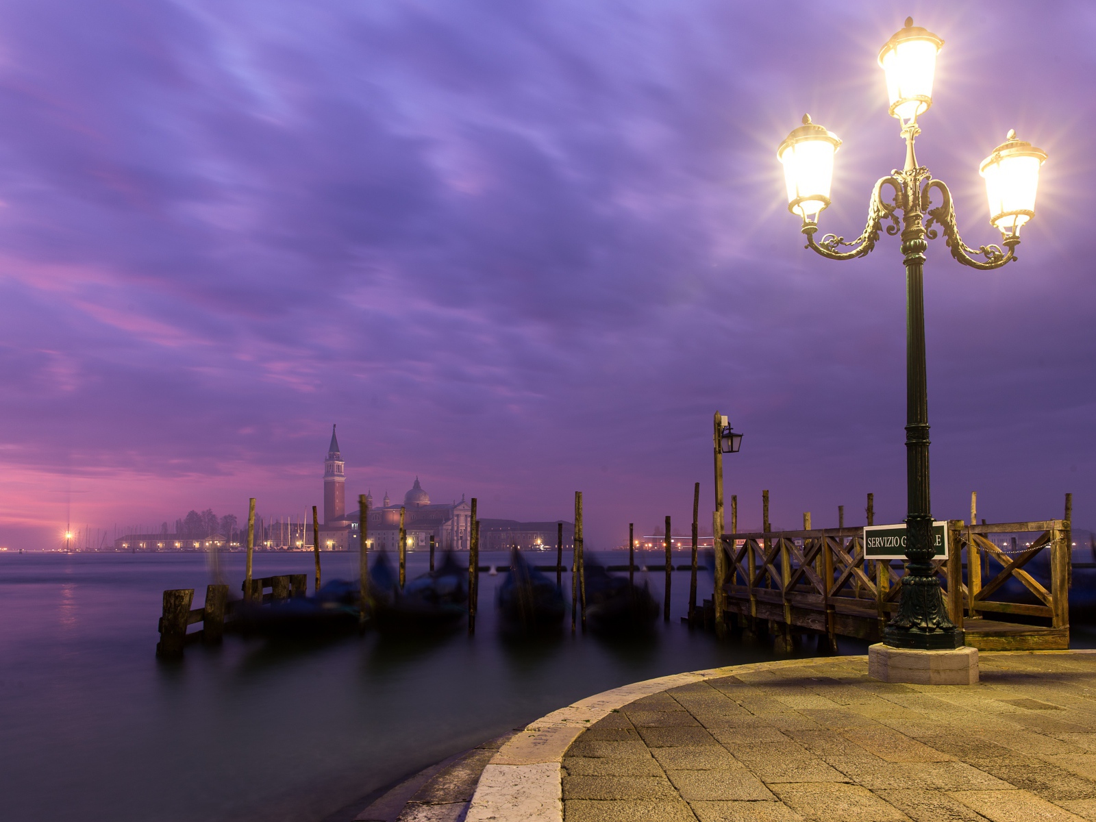 Зажженный фонарь на берегу реки ночью 