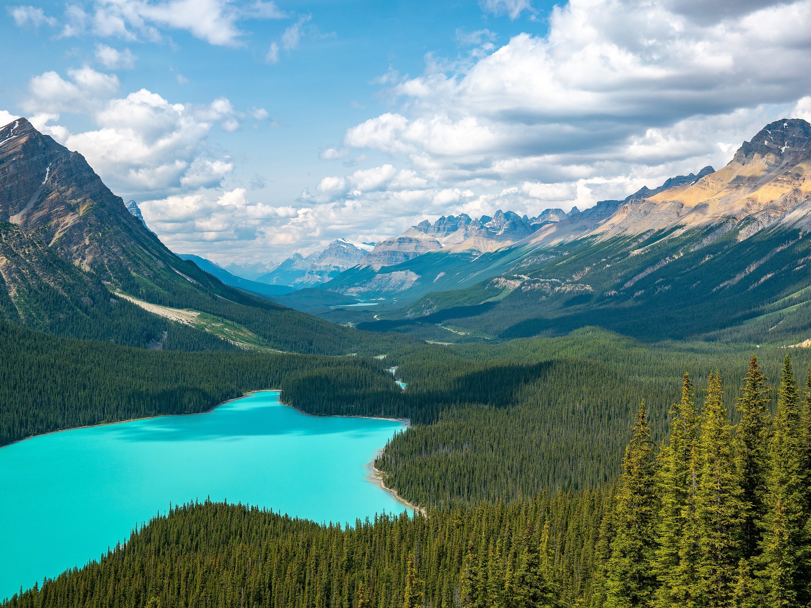 Вид на красивое голубое озеро и горную долину под солнечным небом с белыми облаками