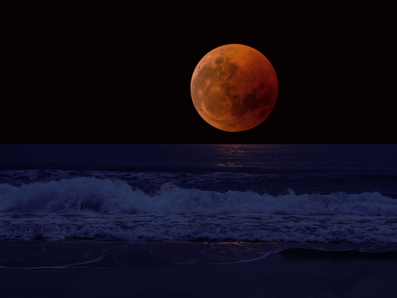 Большая красная луна в темном небе над морем
