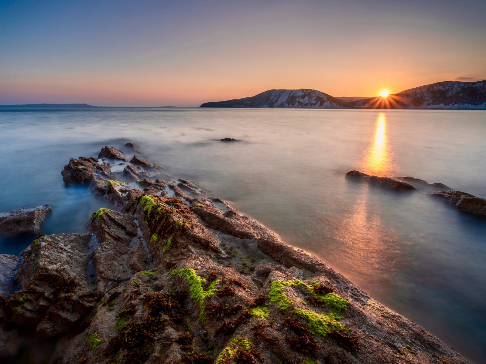 Спокойная вода в море с подводными камнями на закате 