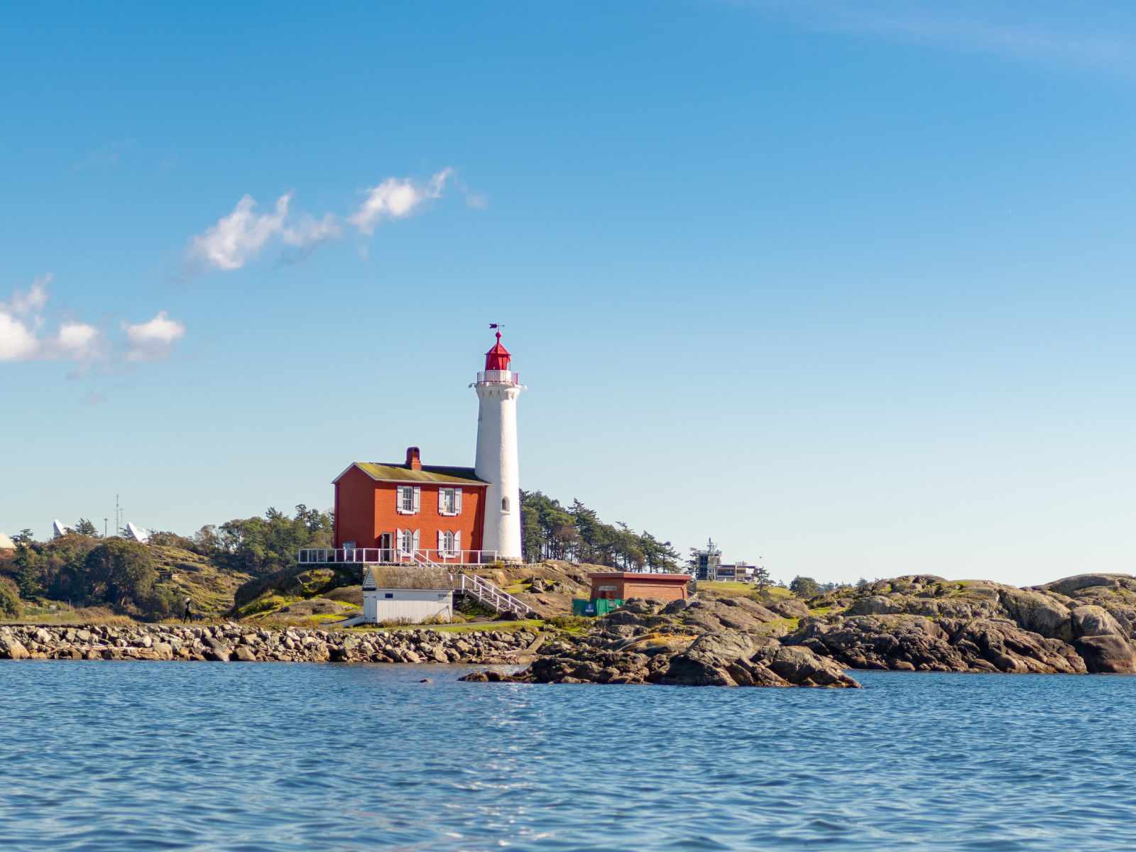 Маяк на каменном берегу моря под голубым небом 