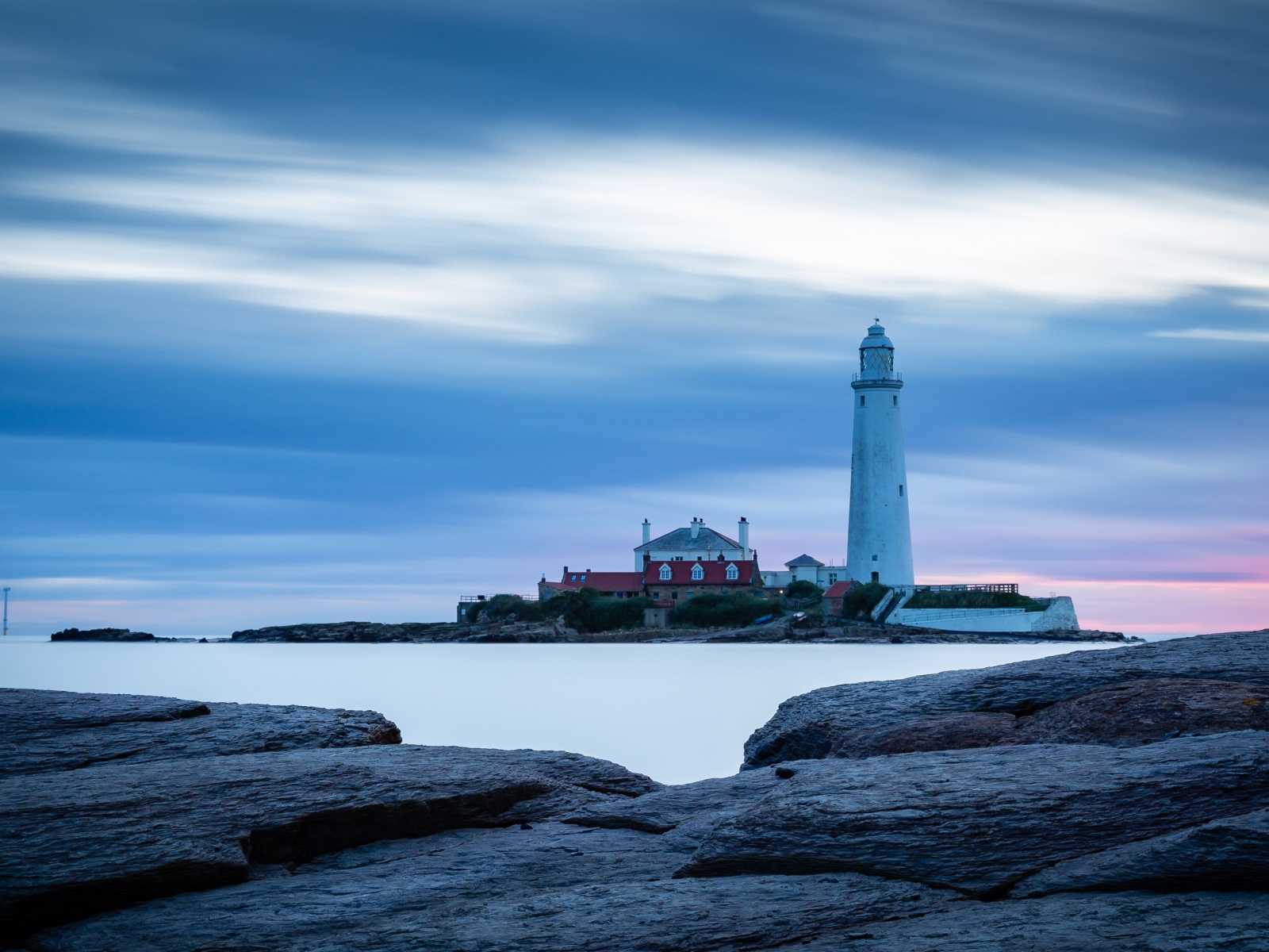 Вид с каменного берега на маяк в море 