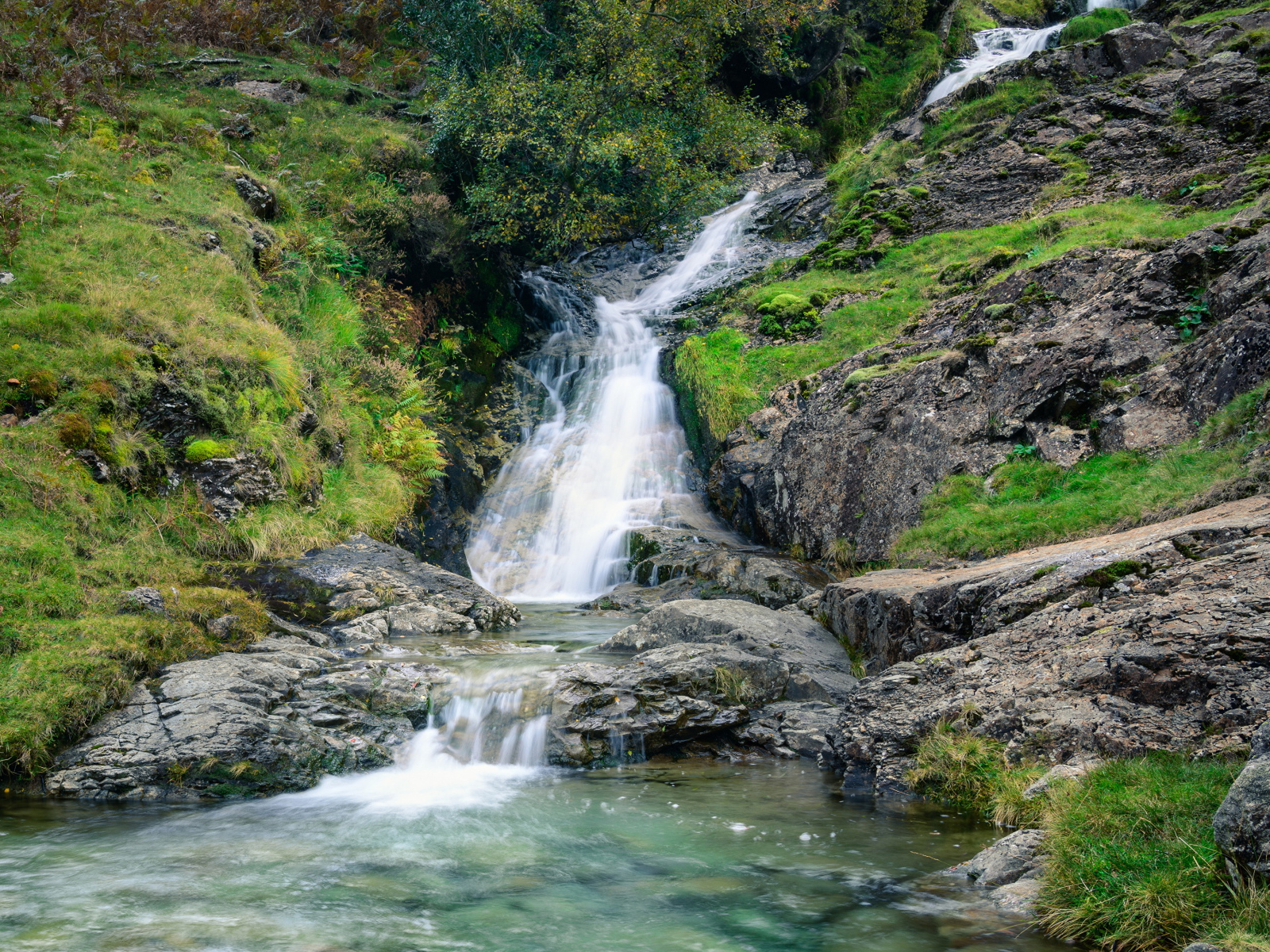 Горный ручей стекает по камням в реку 