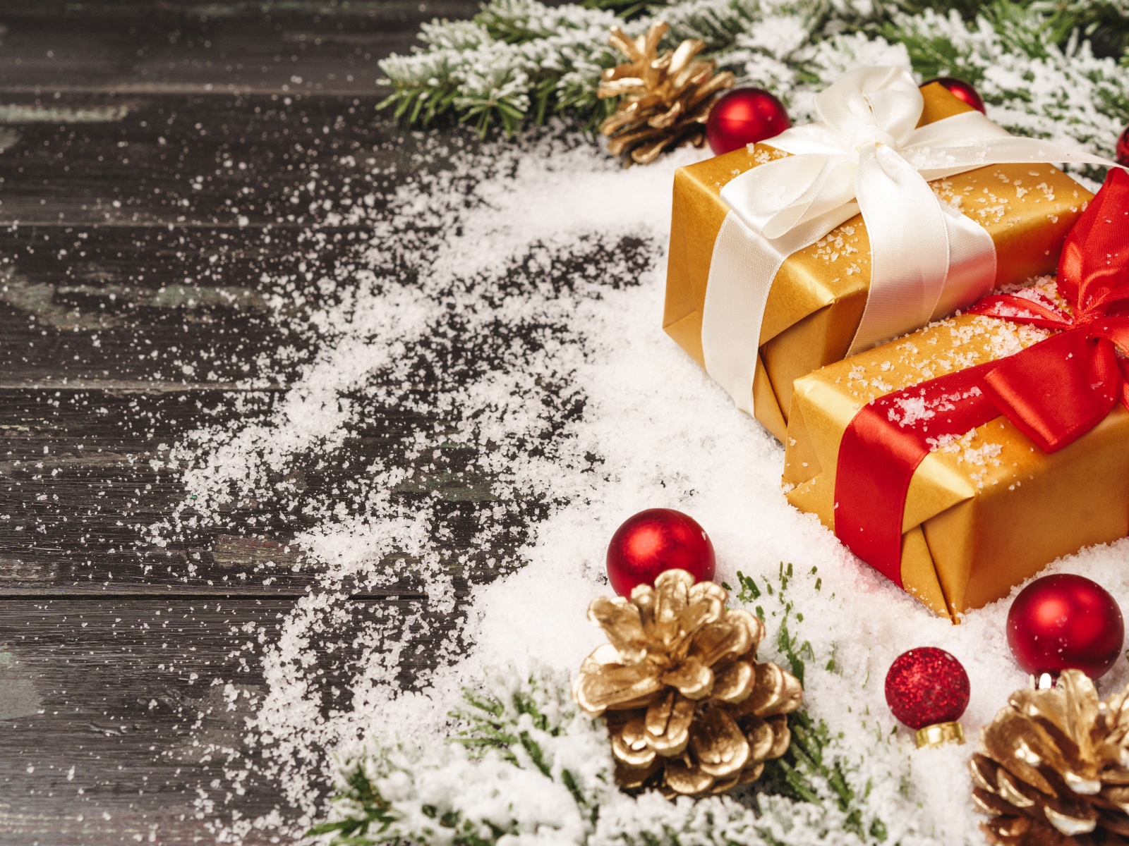 Два новогодних подарка на столе с еловыми ветками 