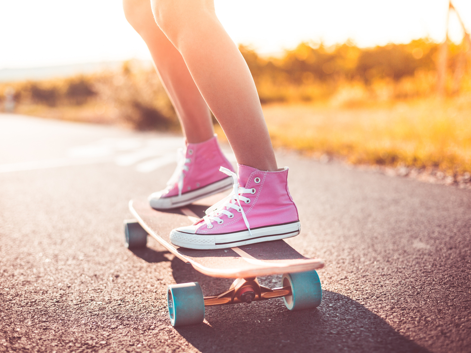 Девочка в розовых кедах едет на скейтборде