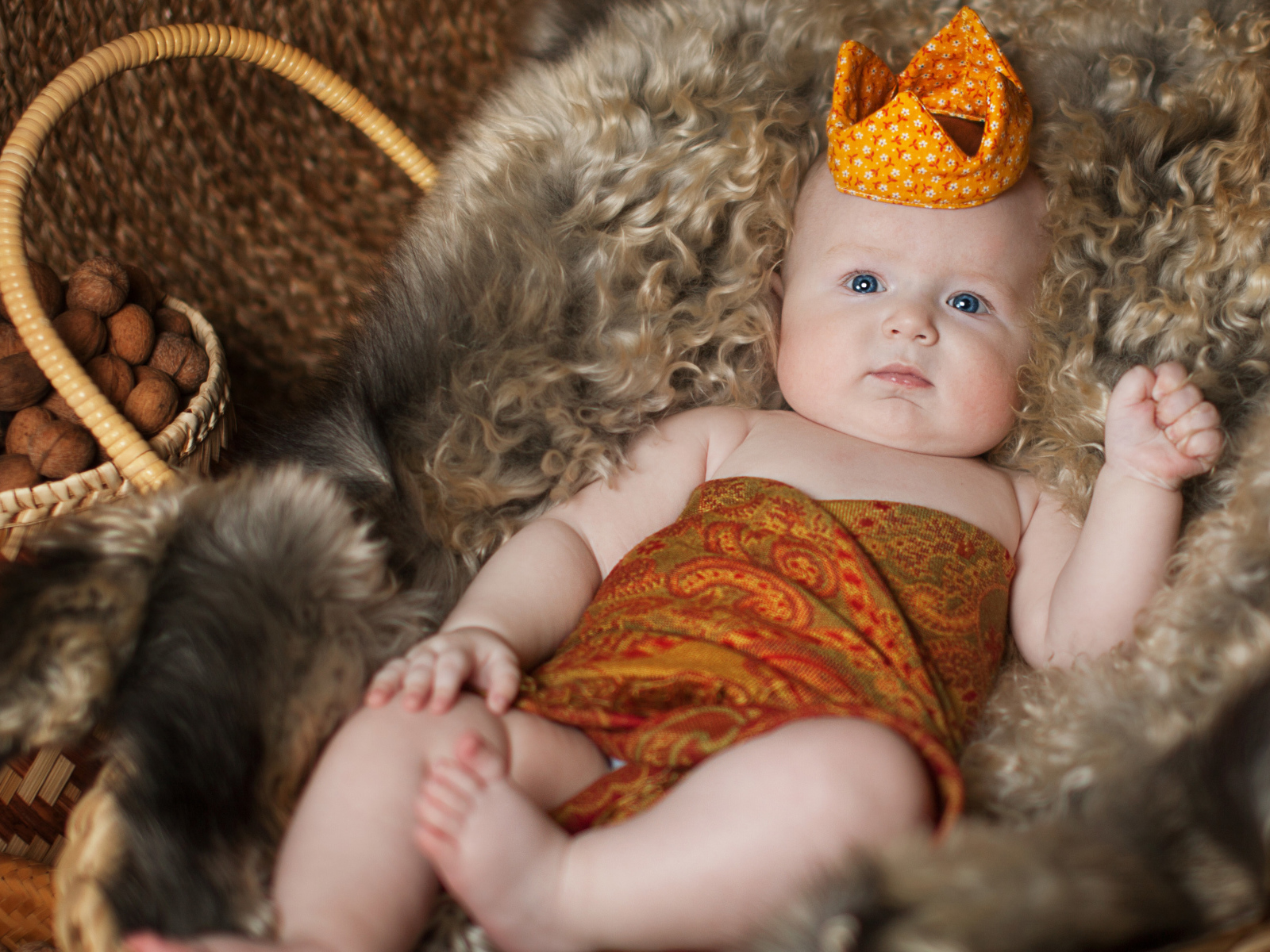 Маленький грудной ребенок в короне лежит в корзине 