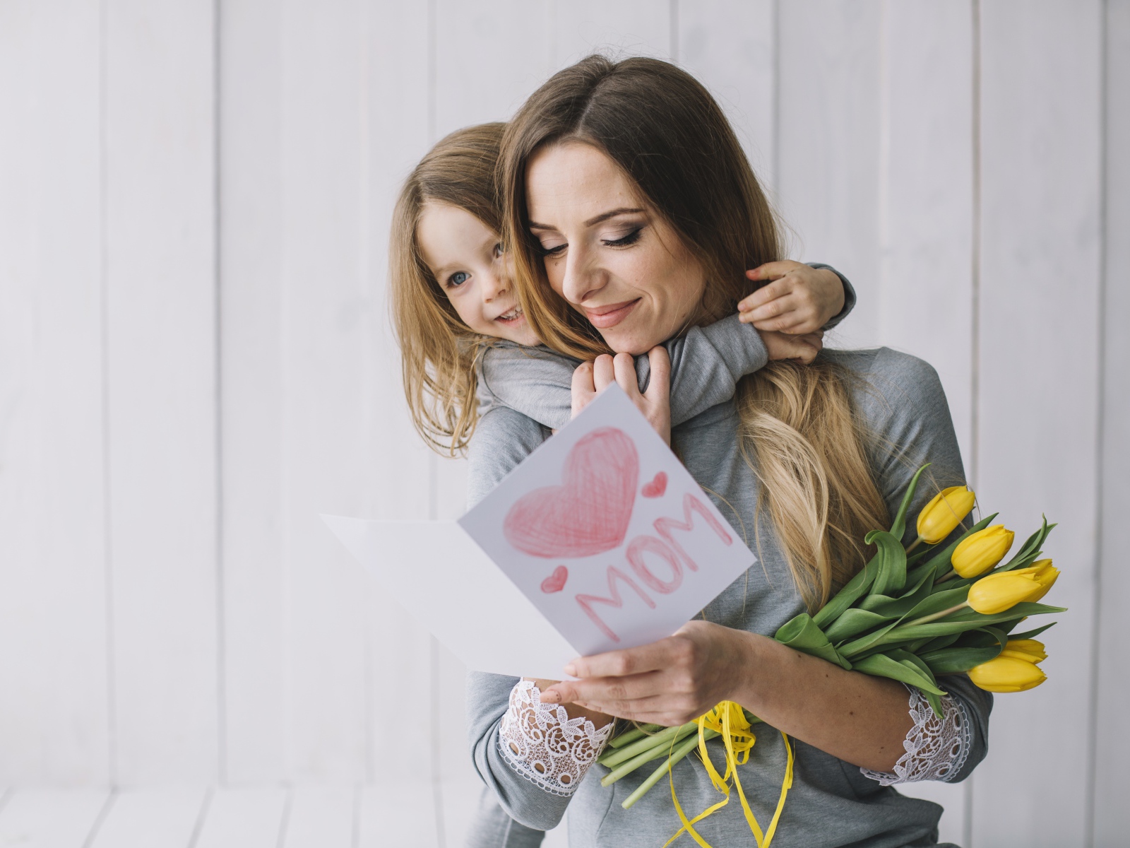 Маленькая девочка подарила маме открытку и букет тюльпанов