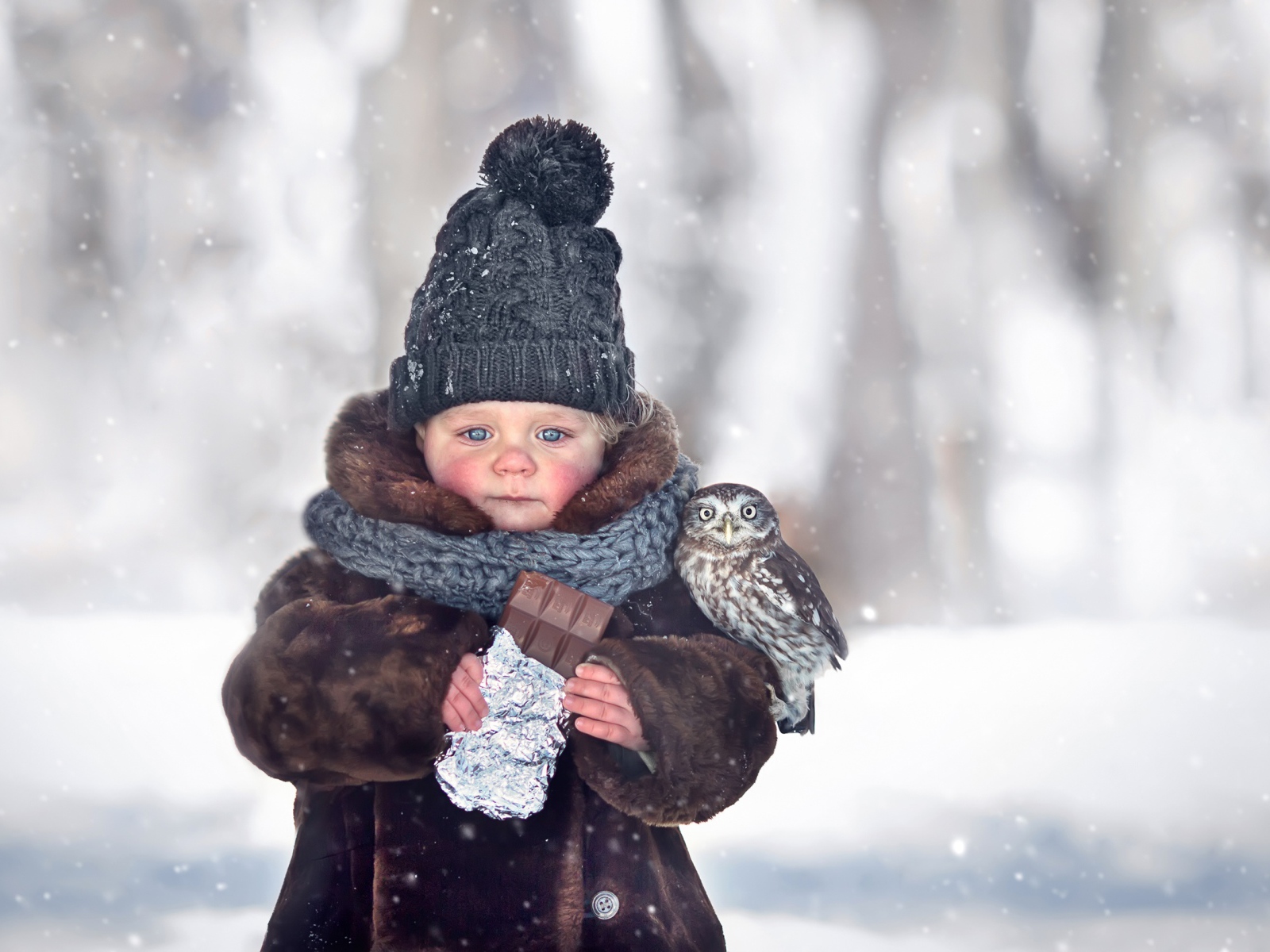 Маленькая девочка с шоколадкой в руках на улице зимой