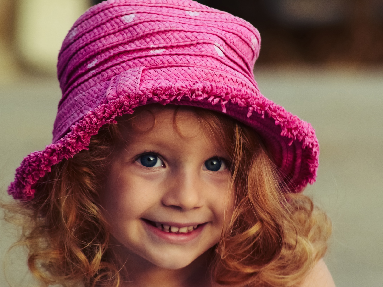 Маленькая улыбающаяся девочка в розовой шляпе