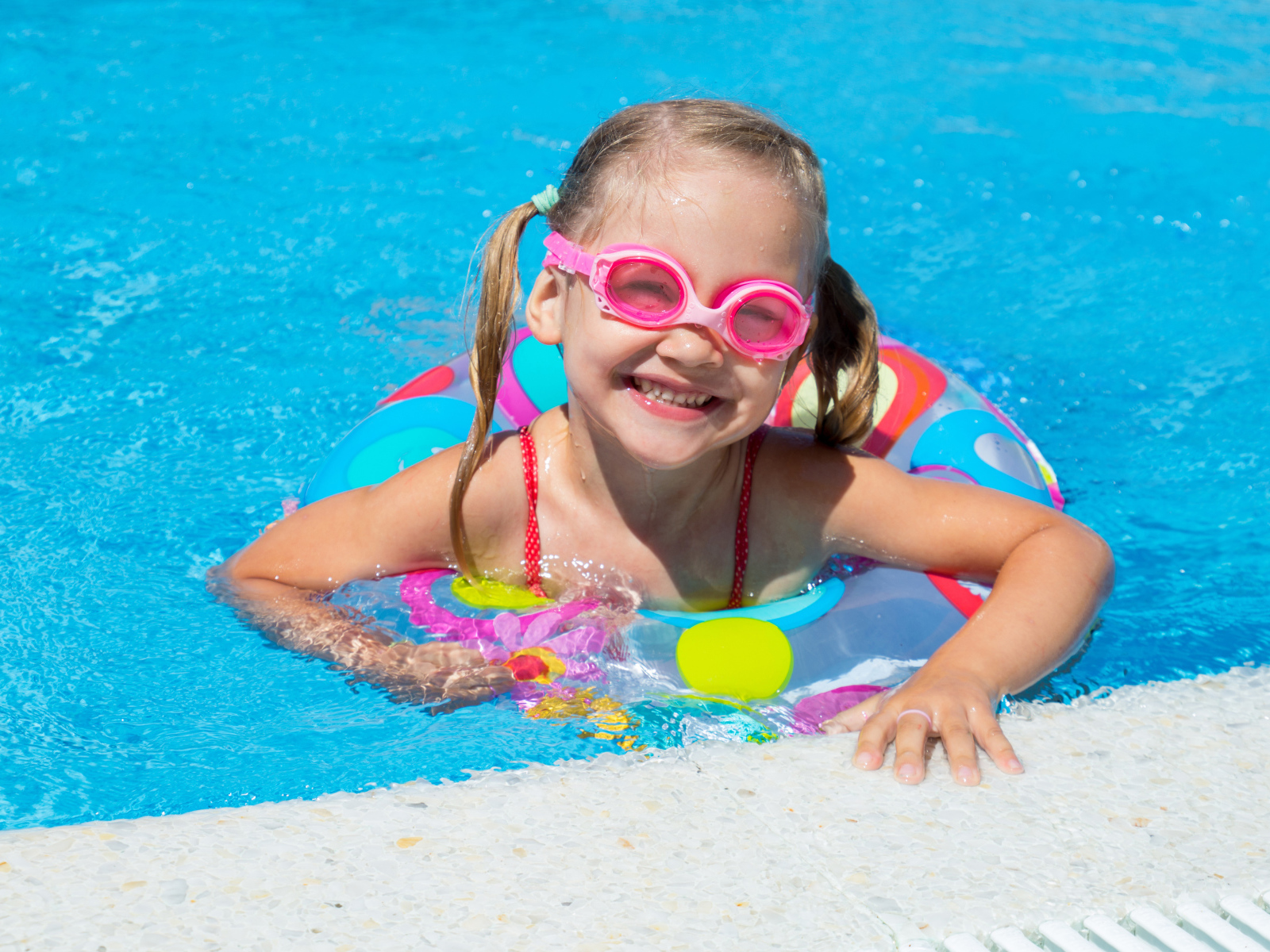 Улыбающаяся девочка с кругом в бассейне 