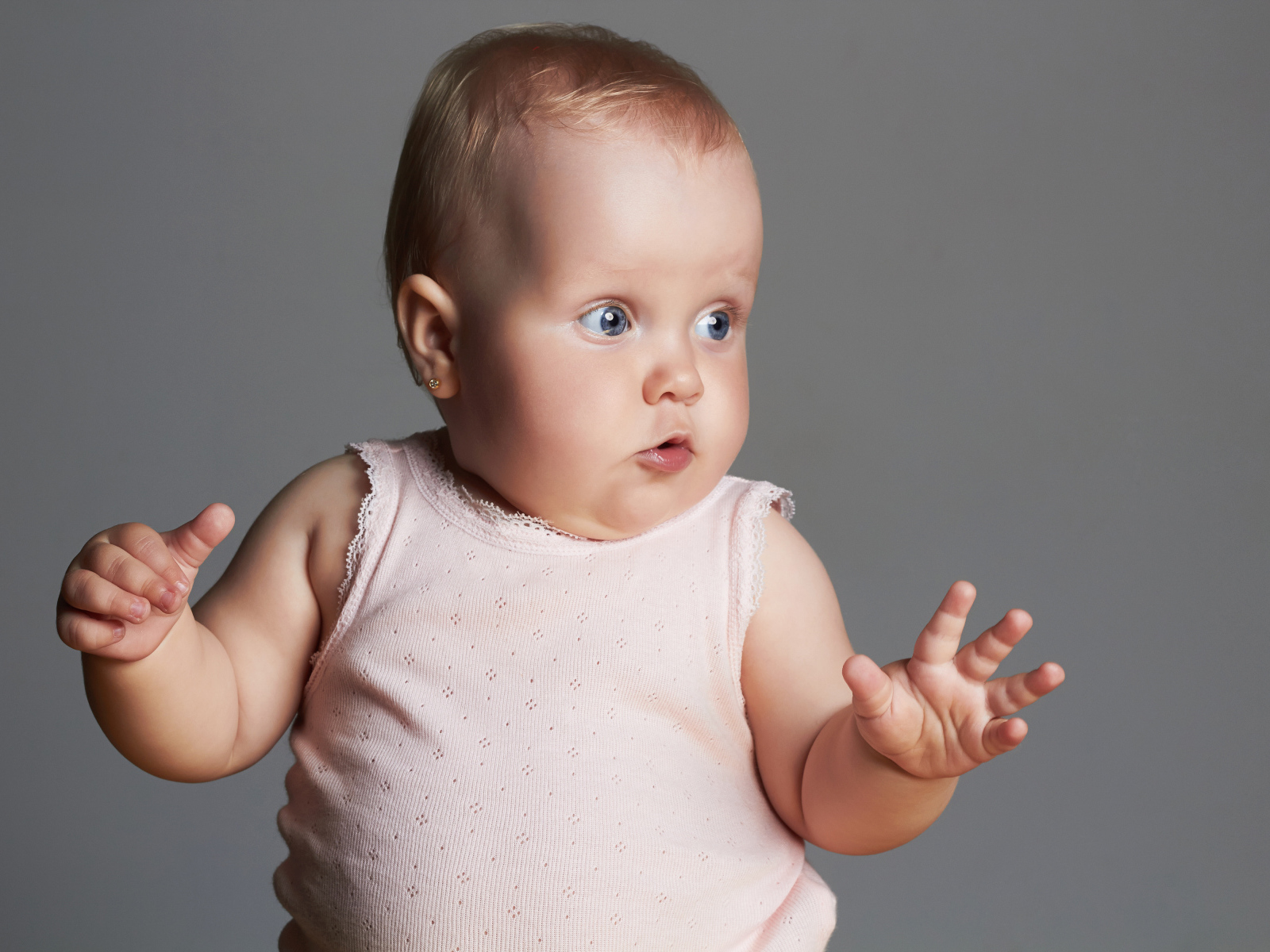 Удивленный маленький ребенок на сером фоне