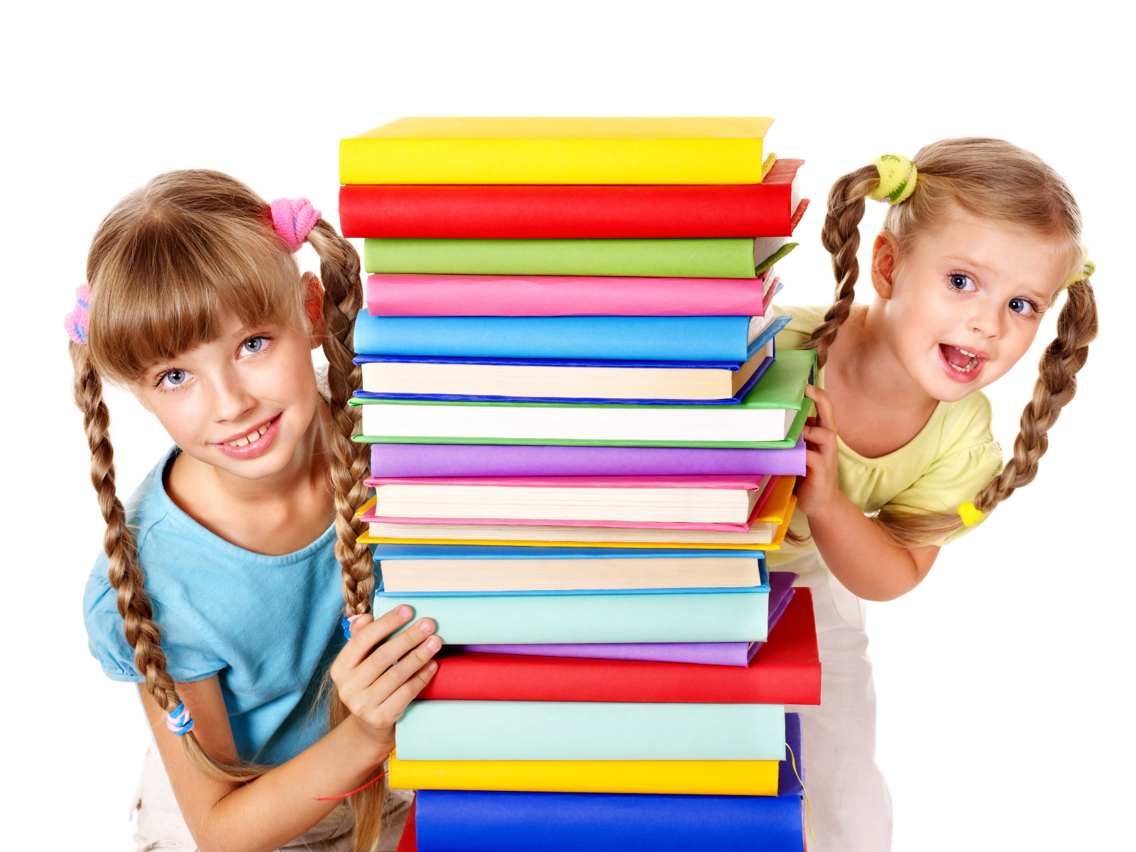 Две маленькие девочки с разноцветными книгами на белом фоне