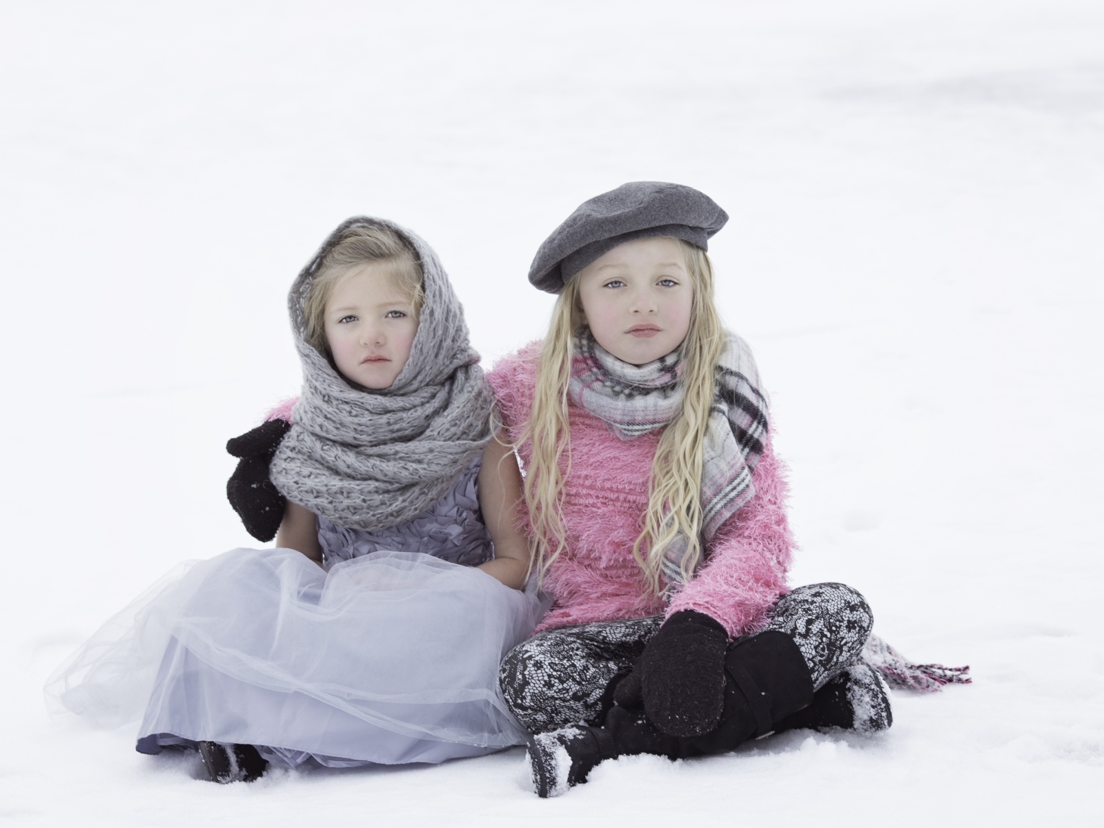 Две маленьких сестры сидят на снегу 
