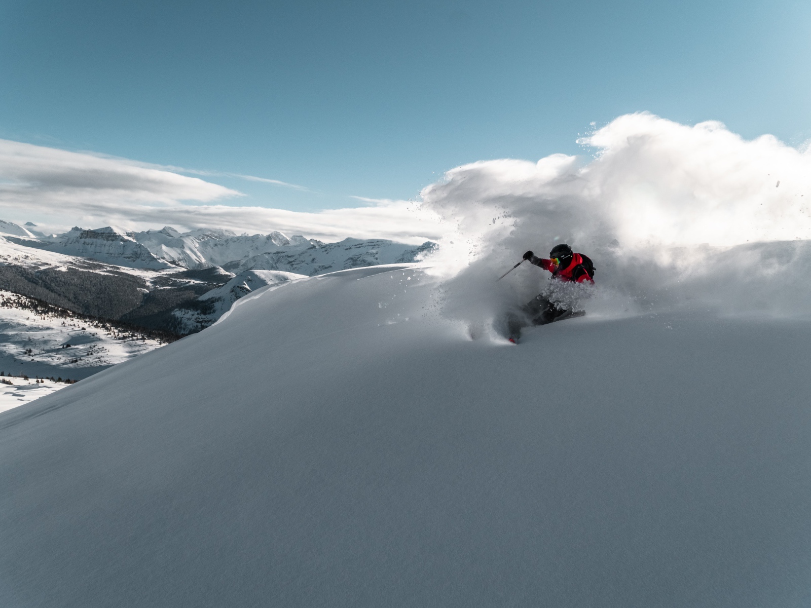 Мужчина спускается на лыжах с горы 