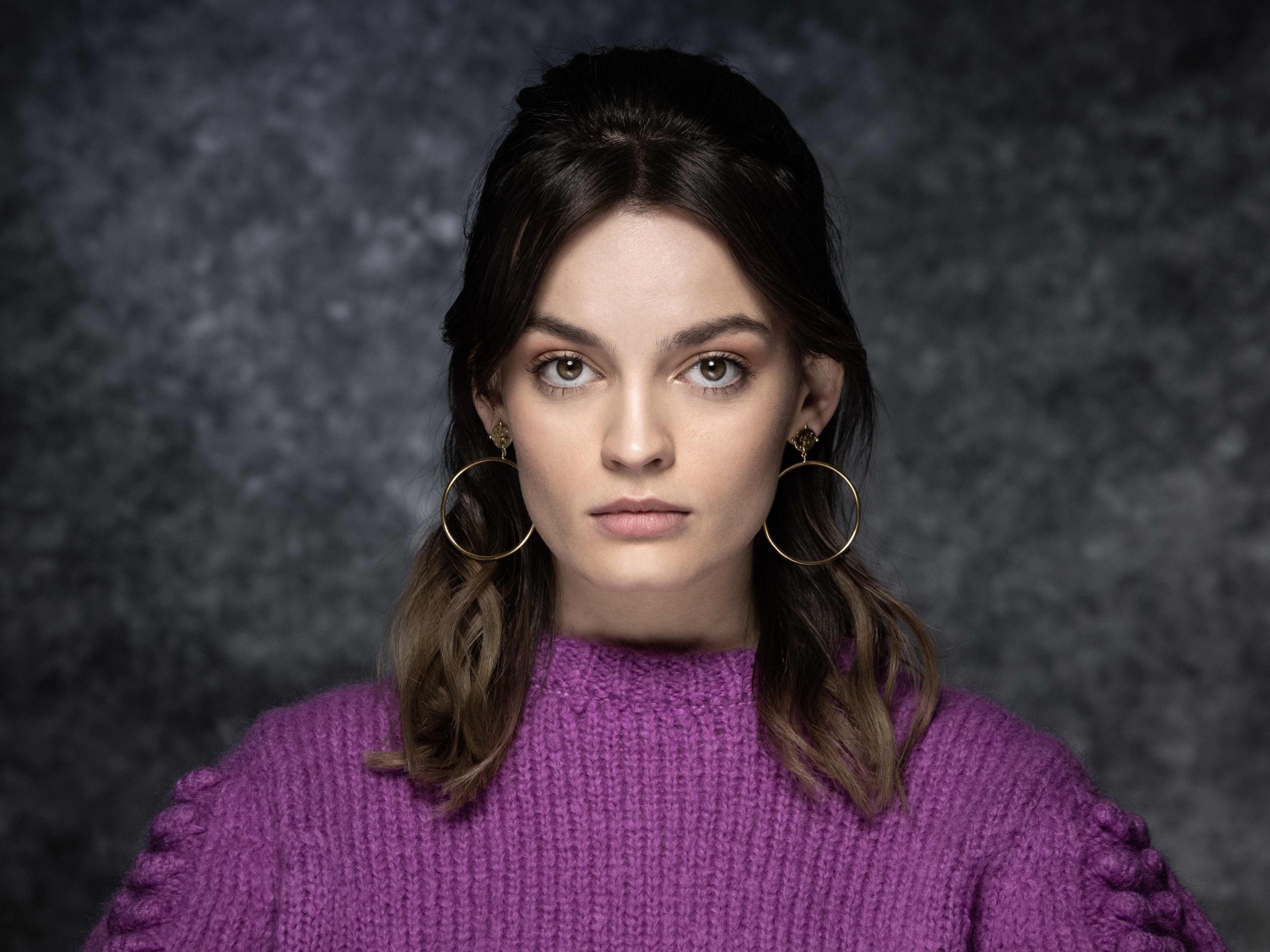 Актриса Эмма Маккей в сиреневом свитере на сером фоне