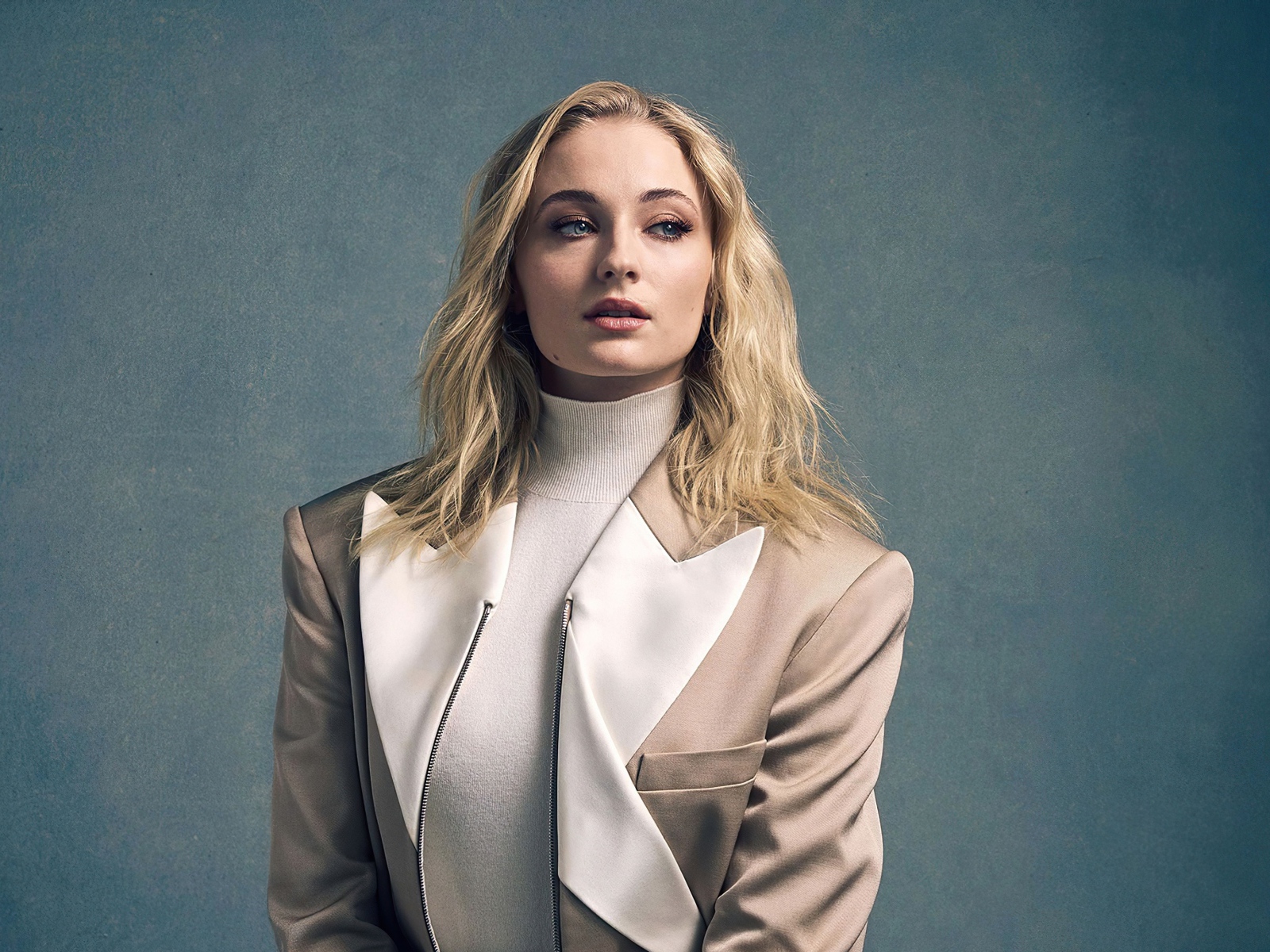Актриса Софи Тёрнер в бежевом костюме на сером фоне