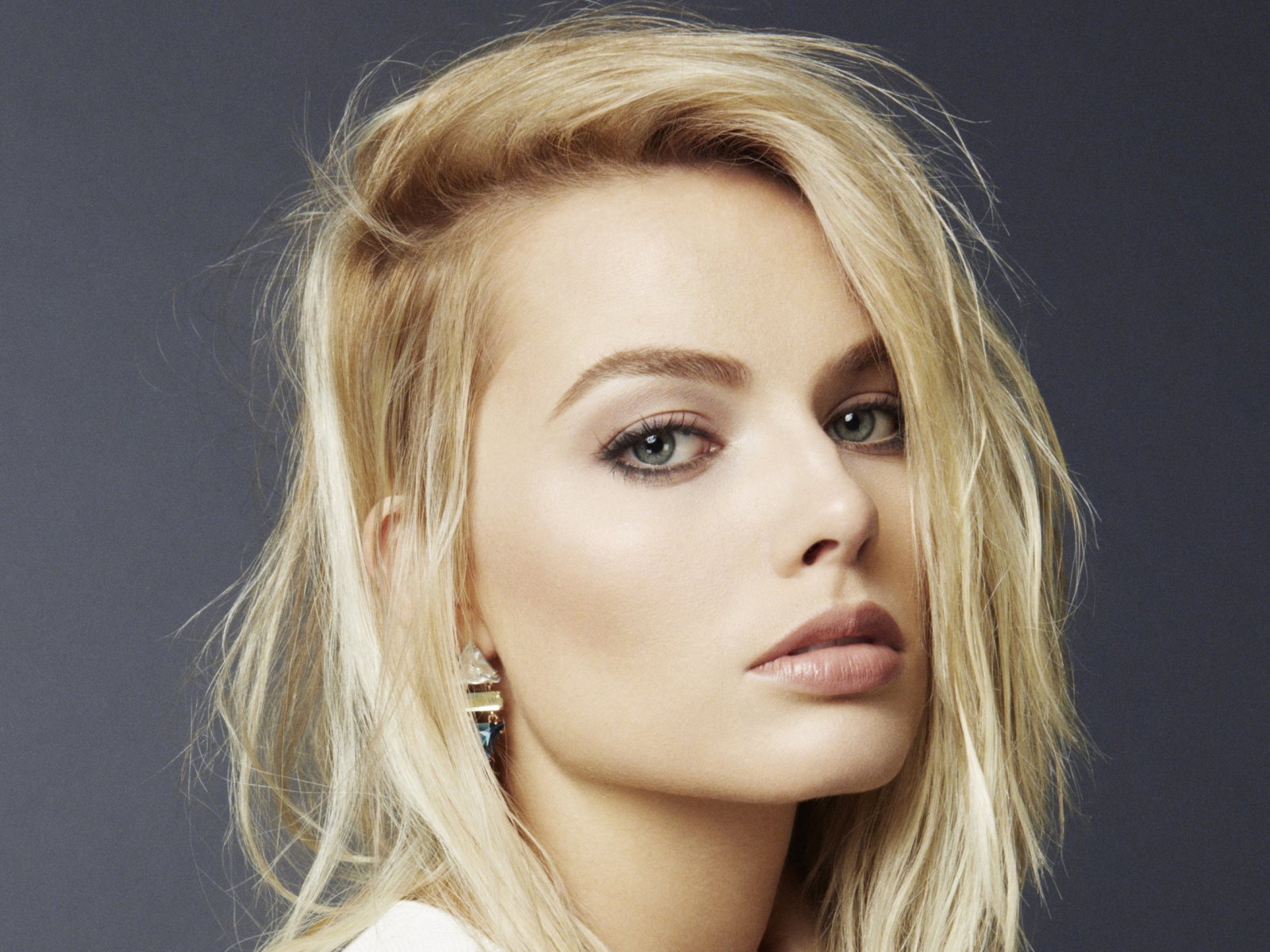 Австралийская актриса Марго Робби крупным планом на сером фоне