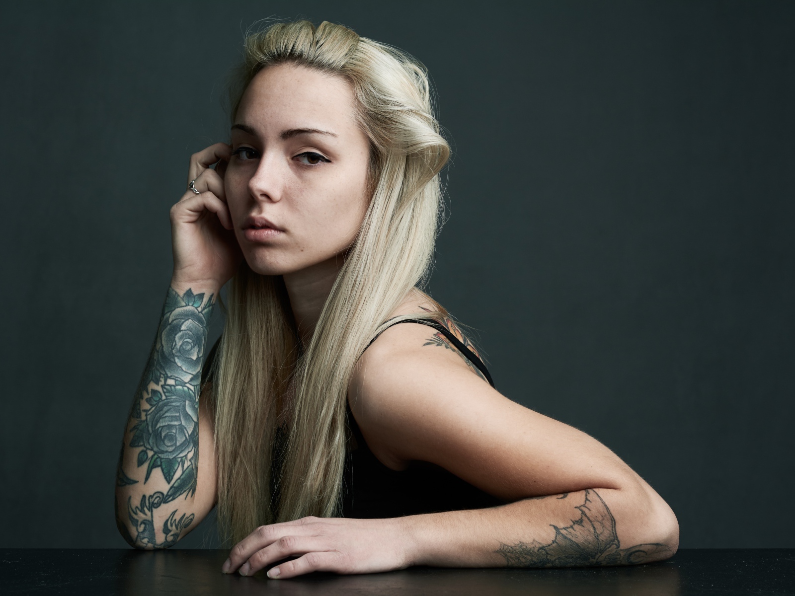 Красивая блондинка с татуировками на теле на сером фоне