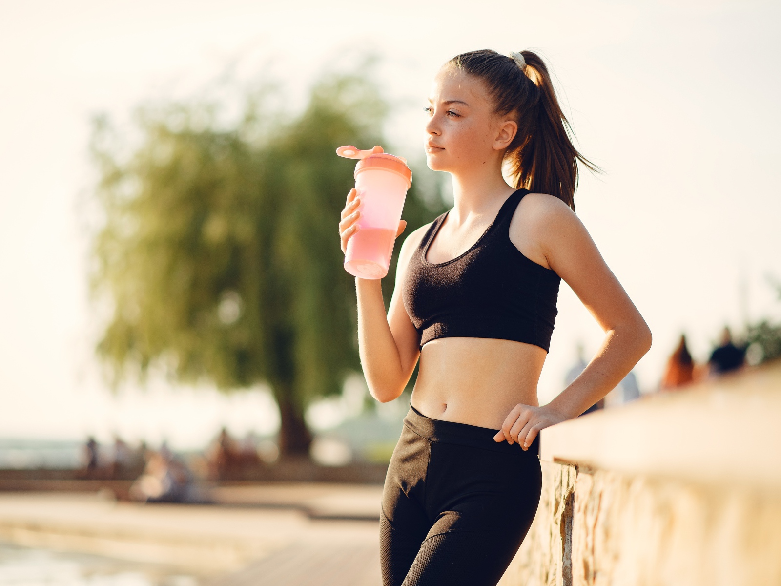 Девушка в черном спортивной форме с водой 