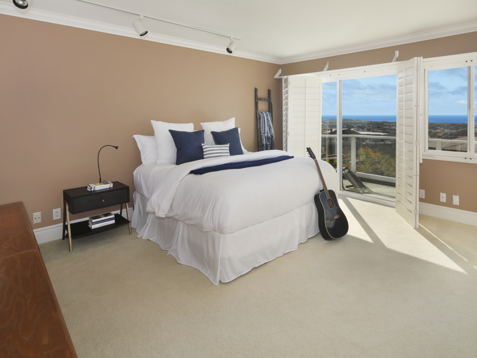 Большая высокая кровать в просторной спальне с гитарой 