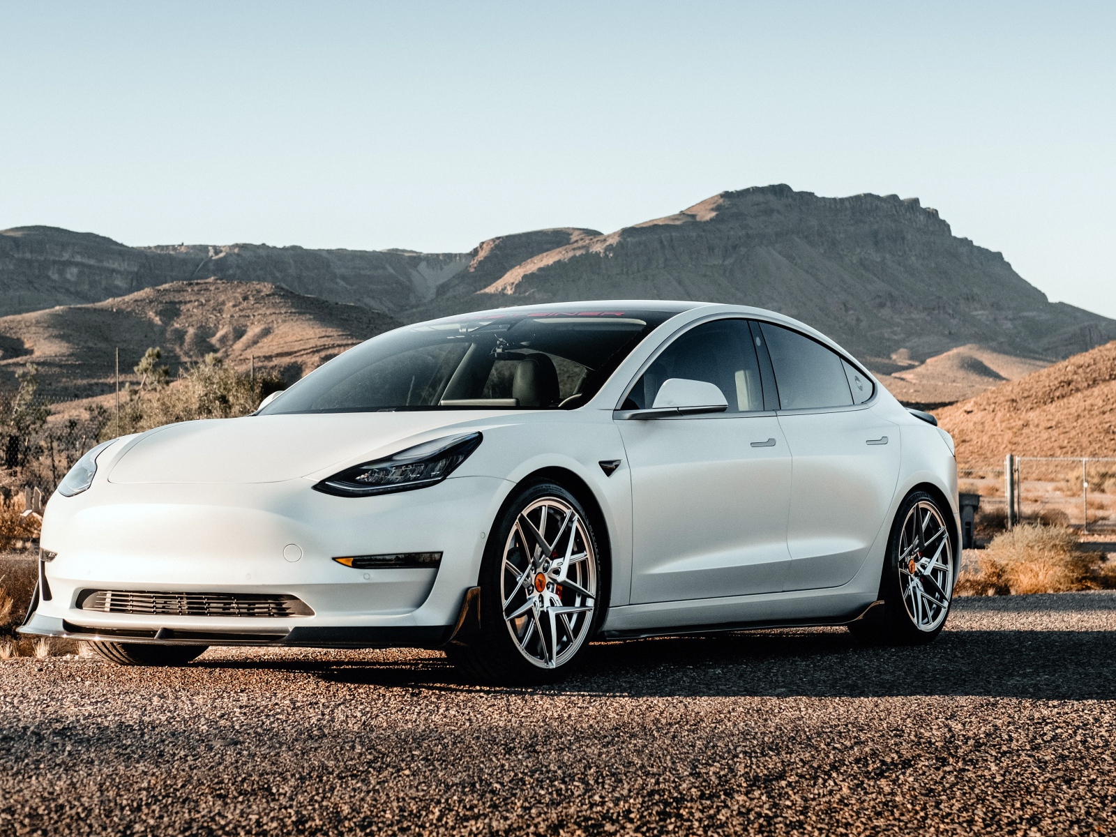 Белый автомобиль Tesla Model 3 Volta 2019 года на фоне гор 