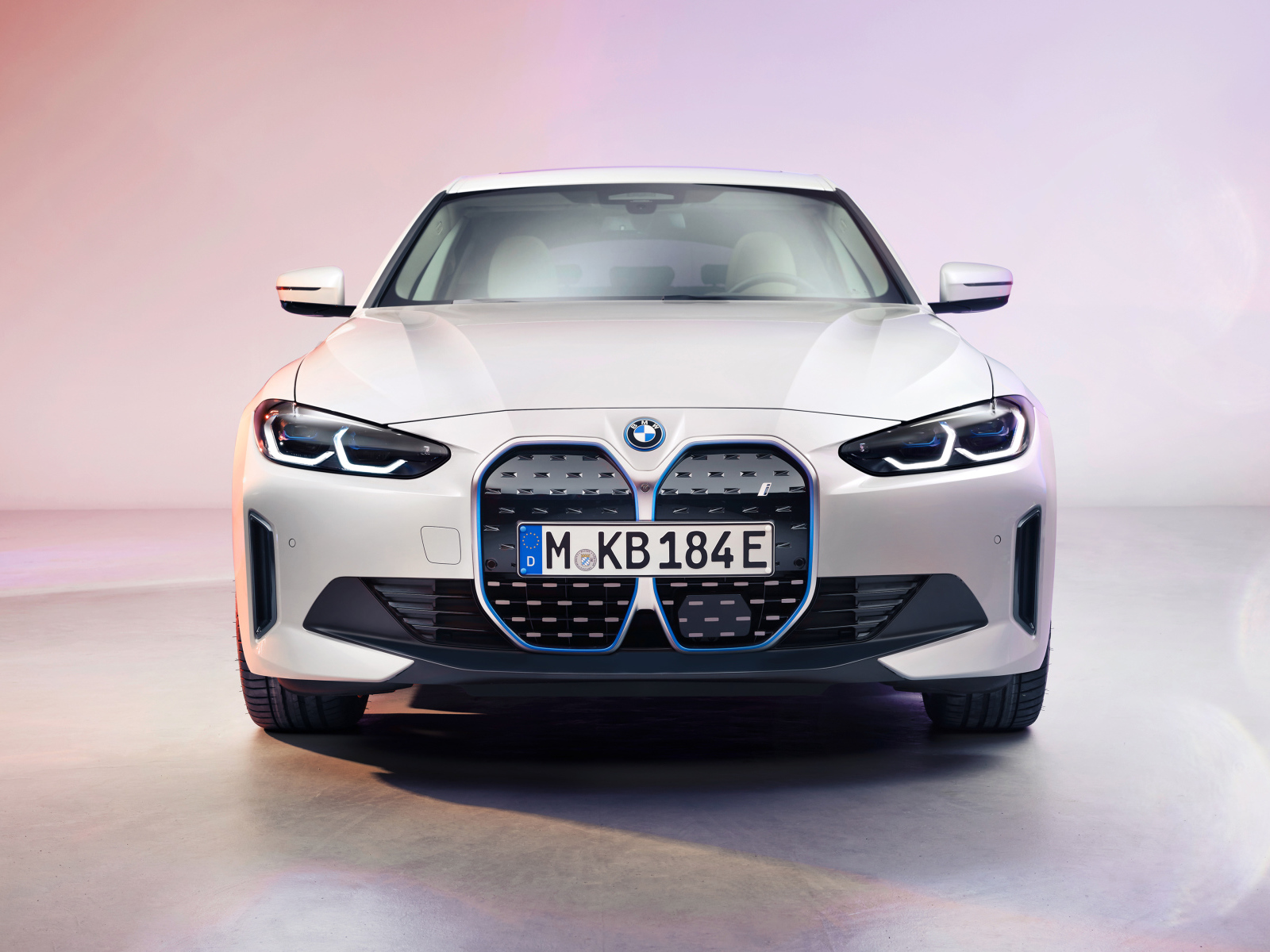 Автомобиль BMW I4 2021 года вид спереди на розовом фоне