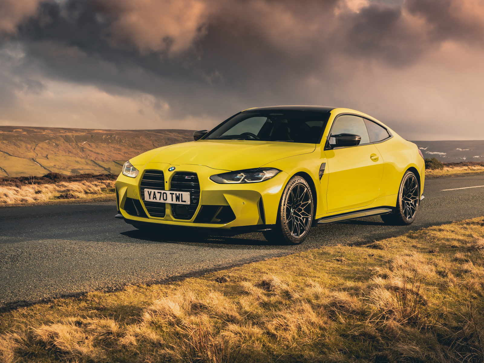 Желтый автомобиль BMW M4 Competition 2021 года на фоне грозового неба