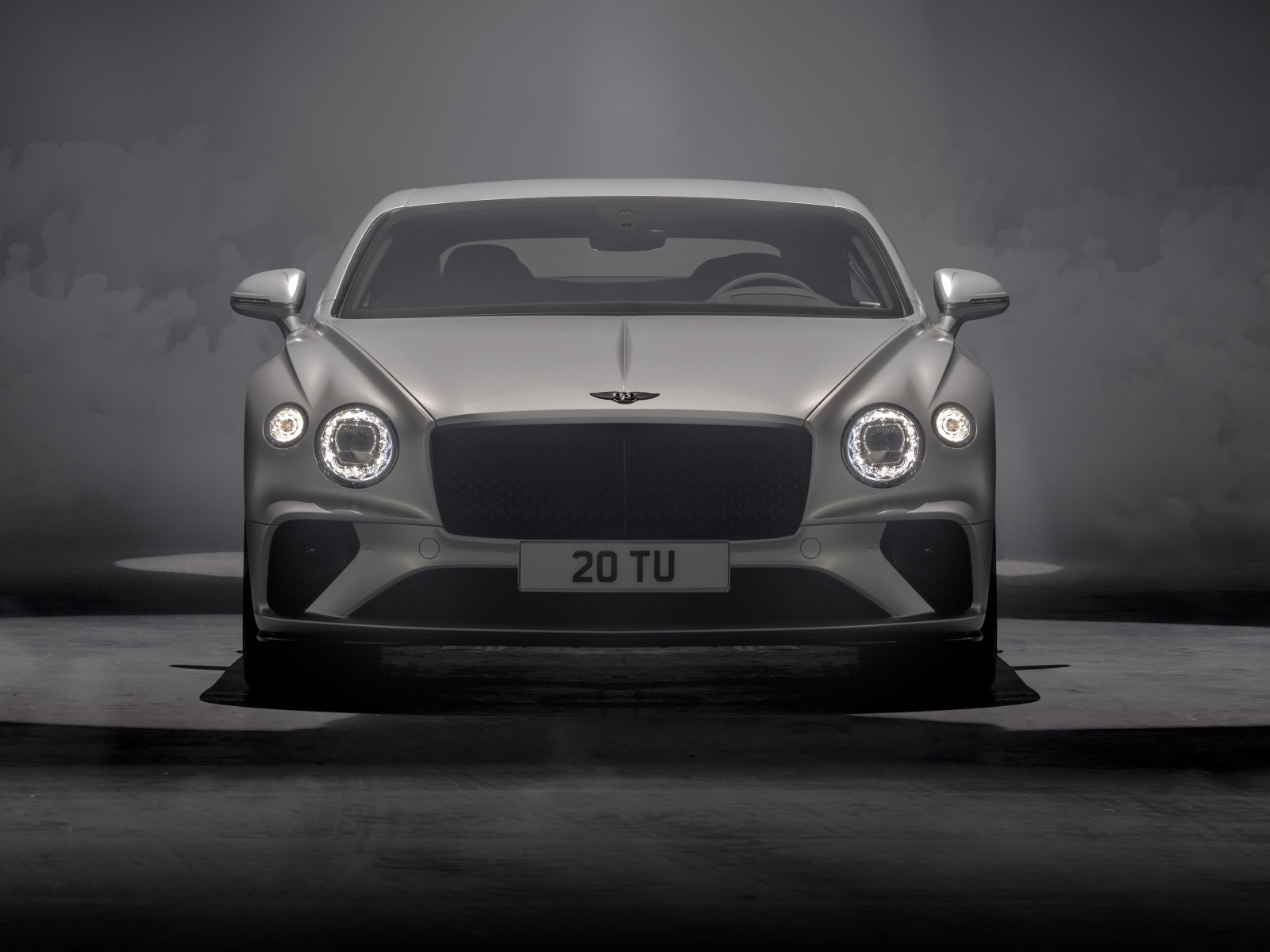 Серебристый автомобиль Bentley Continental GT Speed 2021 года на сером фоне