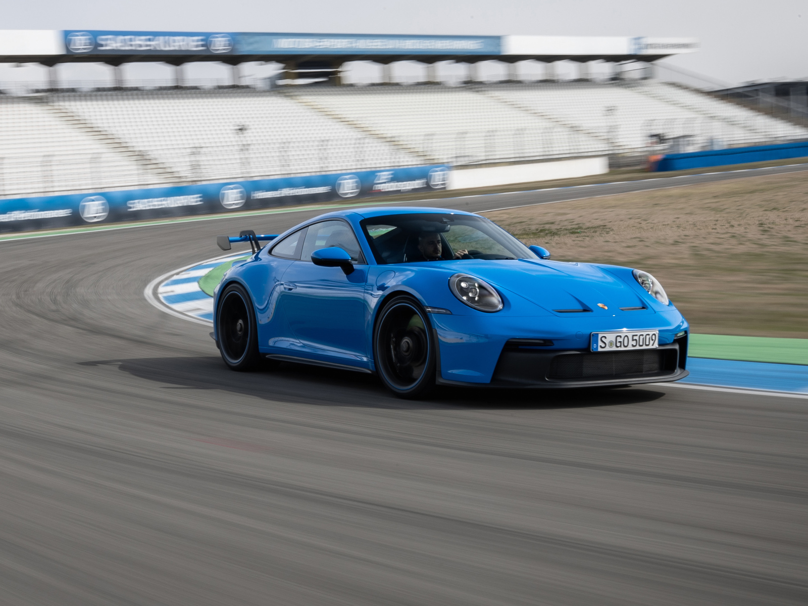 Голубой автомобиль Porsche 911 GT3 2021 года на стадионе