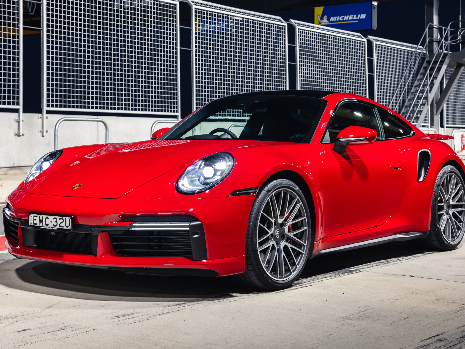 Красный автомобиль Porsche 911 Turbo 2021 года на стадионе