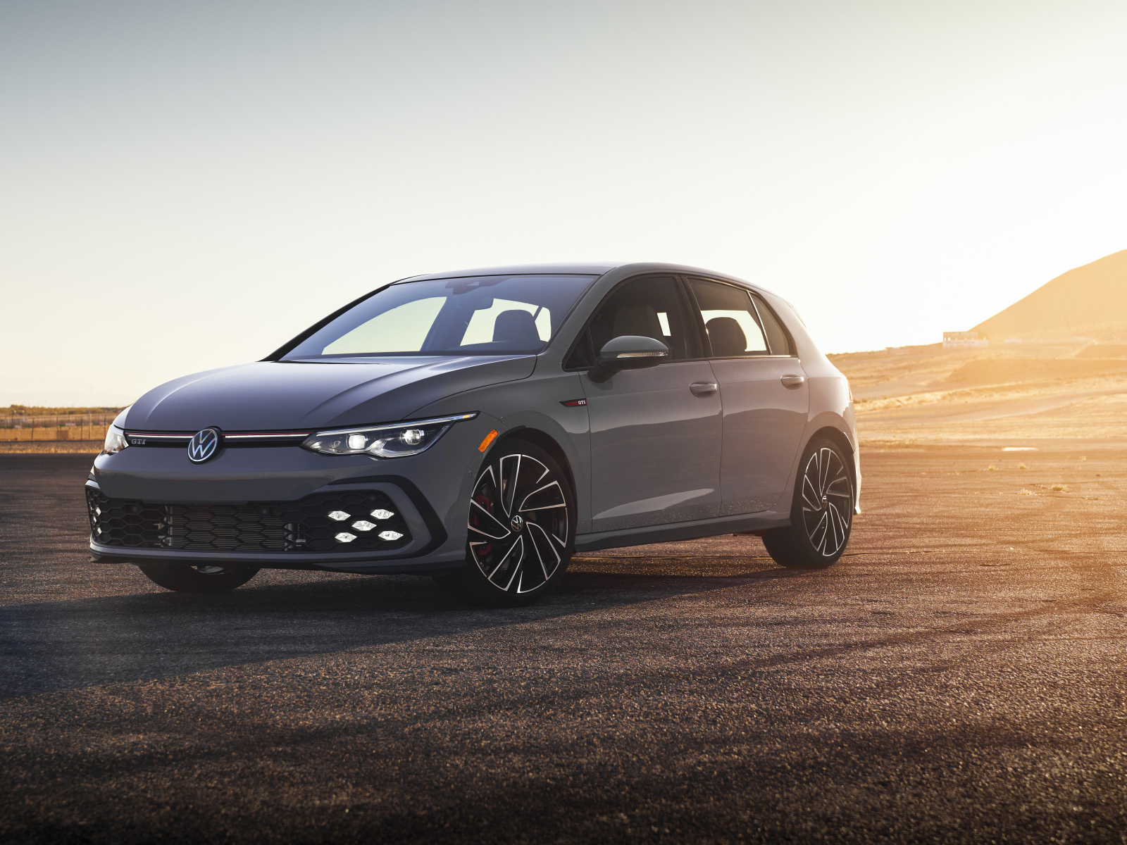 Серебристый автомобиль Volkswagen Golf GTI на фоне заката