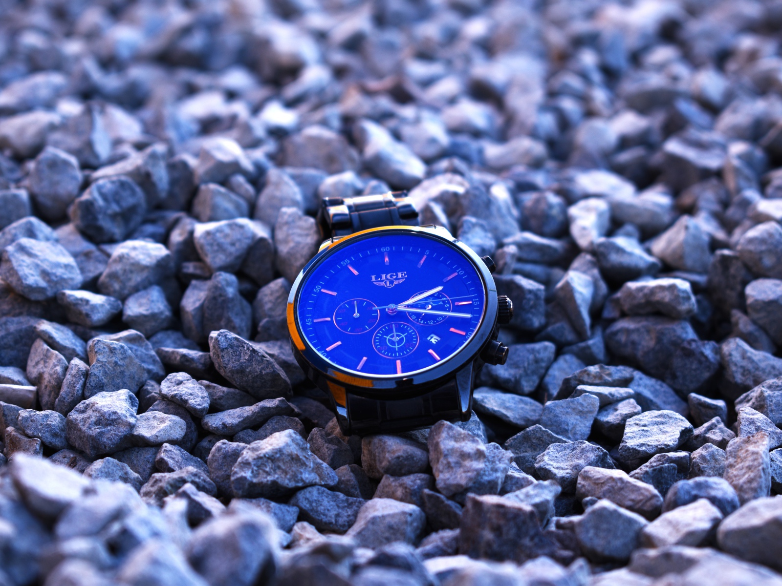 Голубые наручные часы лежат на камнях