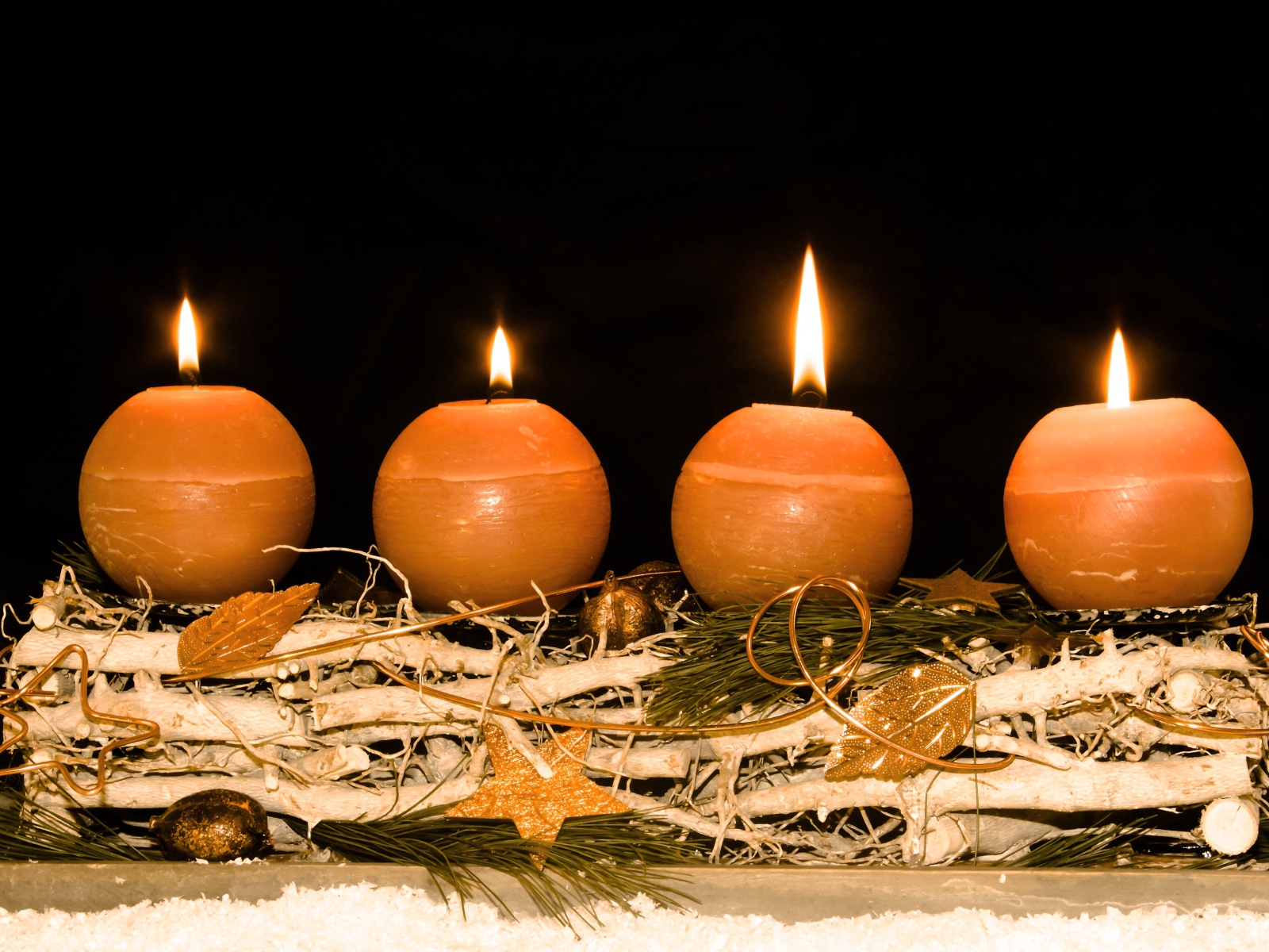 Четыре круглые зажженные свечи на черном фоне