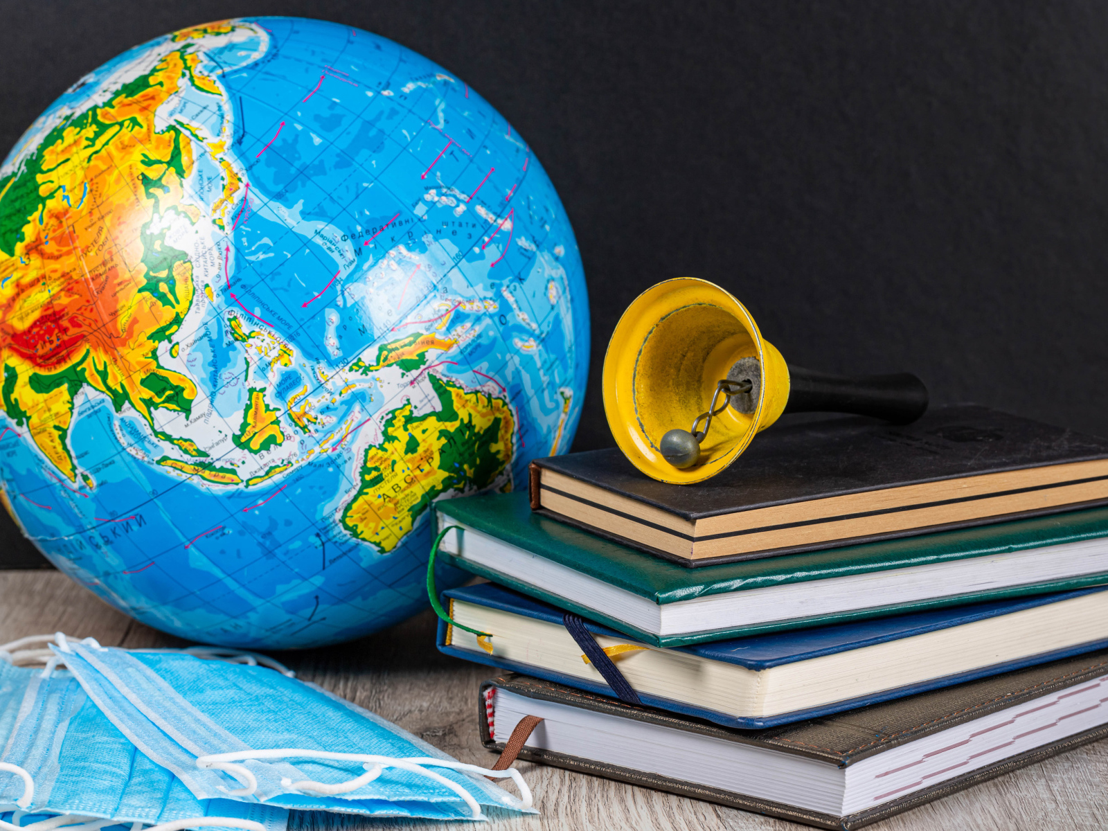 Глобус, книги, колокольчик и медицинские маски 