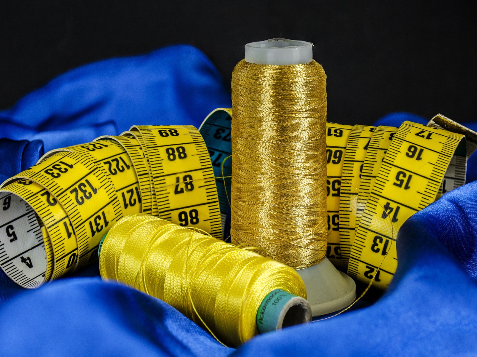 Золотые нитки и сантиметр на голубой ткани 