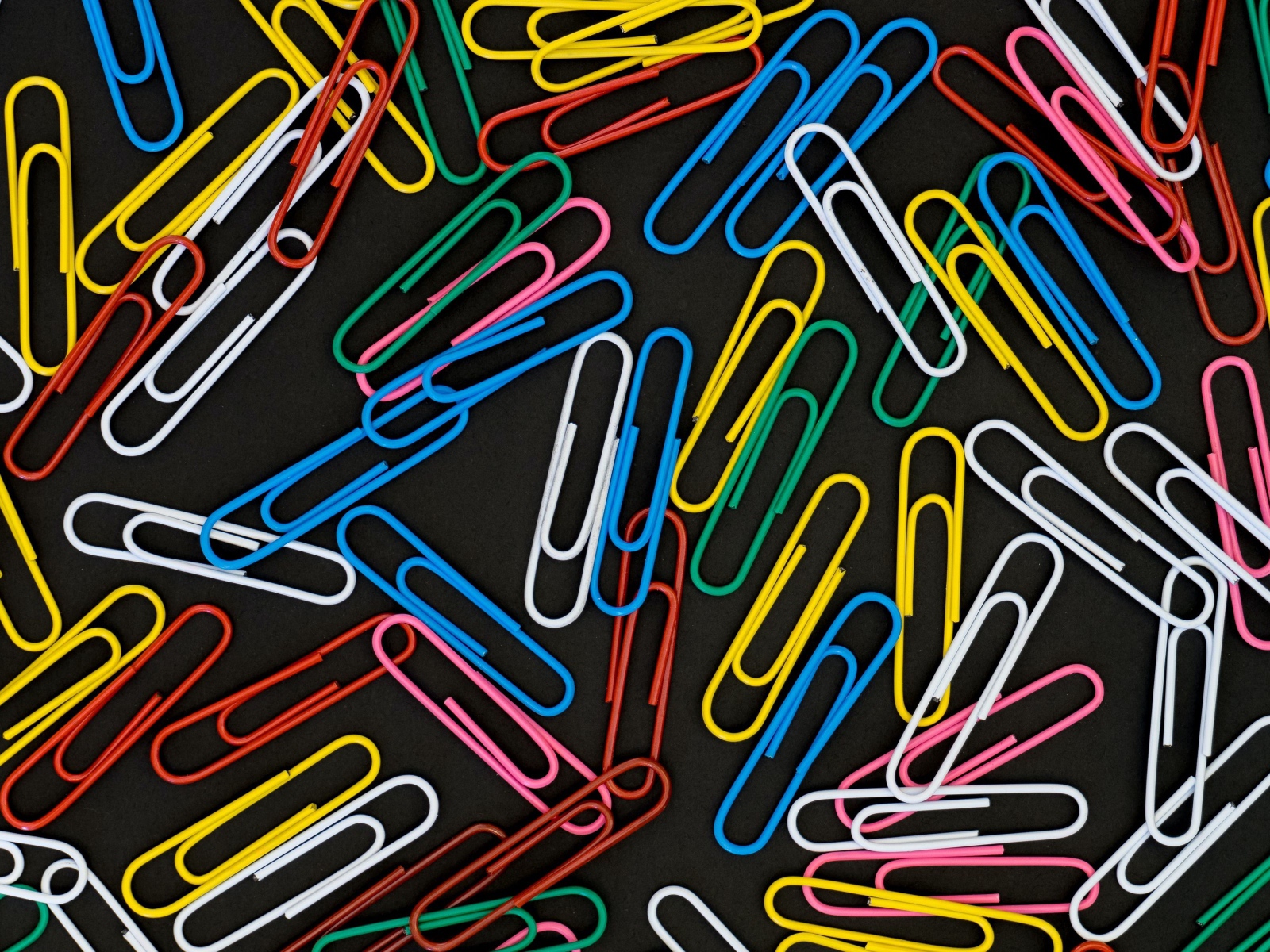 Много разноцветных скрепок на черном фоне