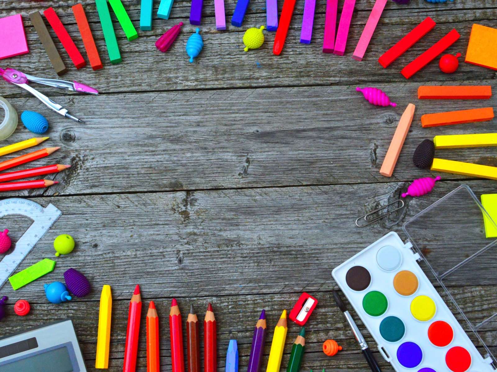 Радуга ярких канцелярских предметов для школы  на деревянном столе