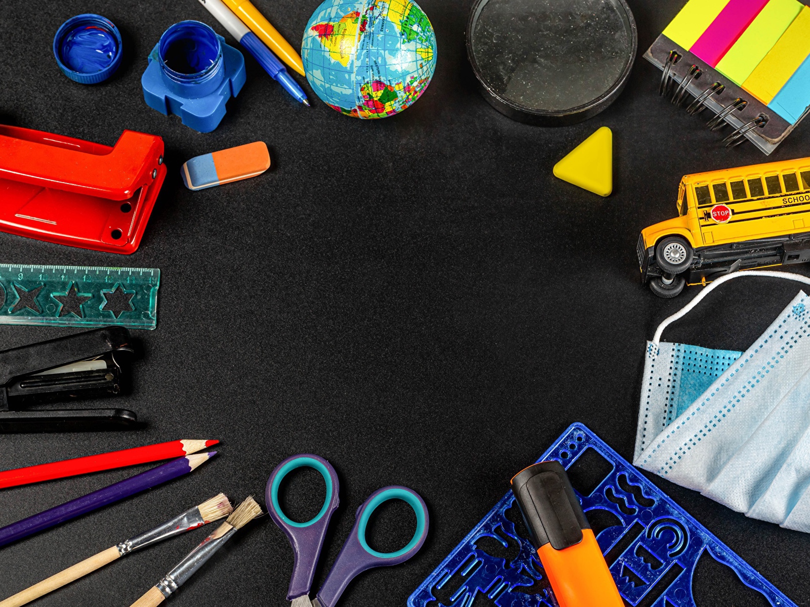 Канцелярские предметы, игрушки и маска на черном столе 