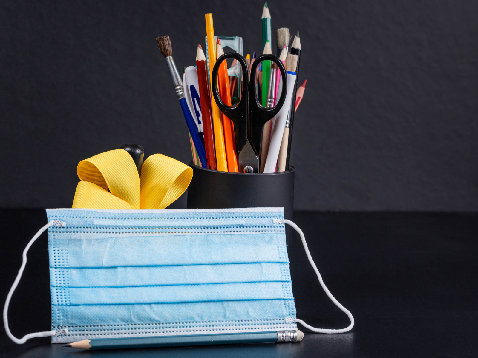 Канцелярские предметы на столе с медицинской маской