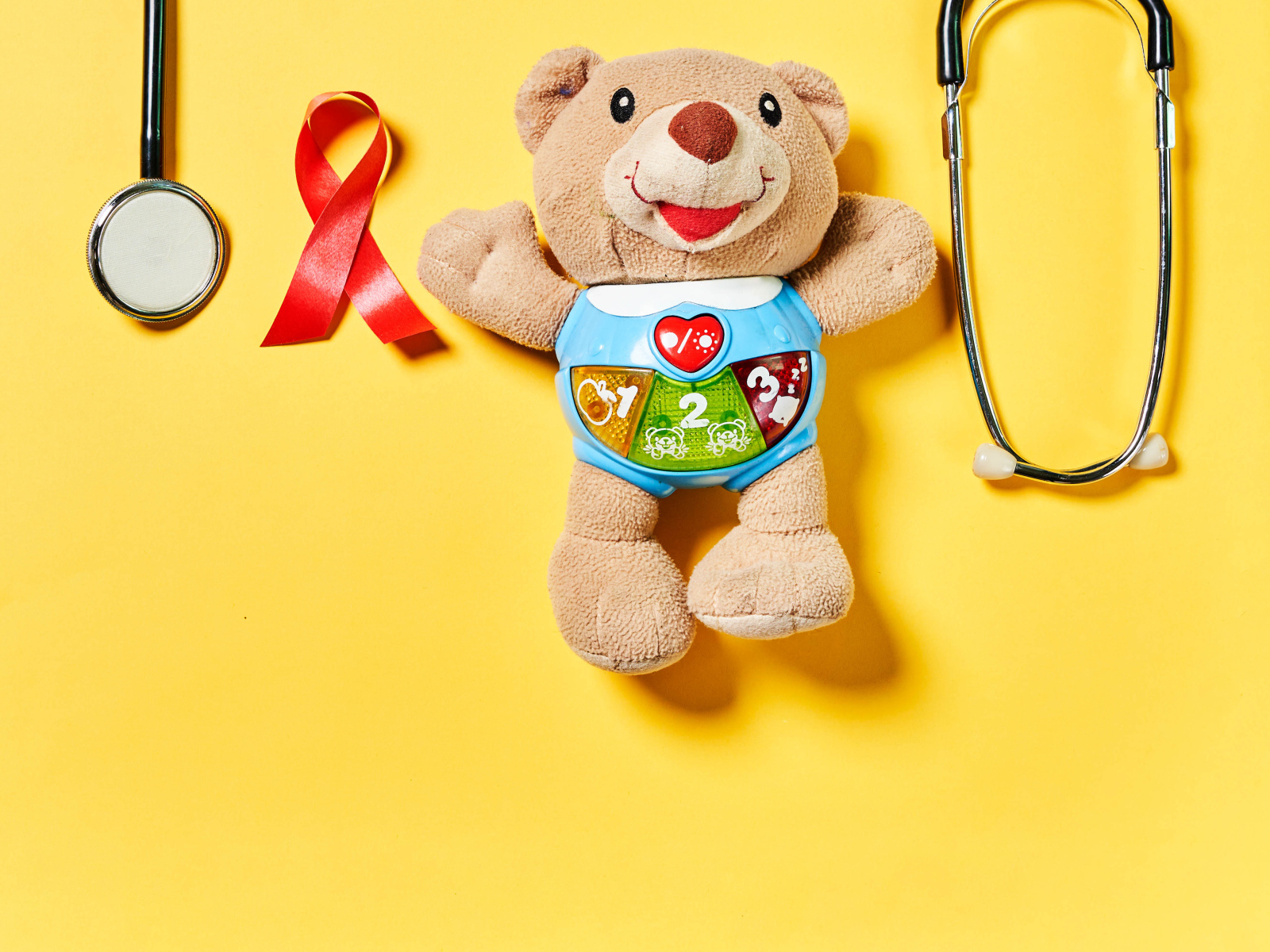 Игрушечный медвежонок с фонендоскопом на желтом фоне 