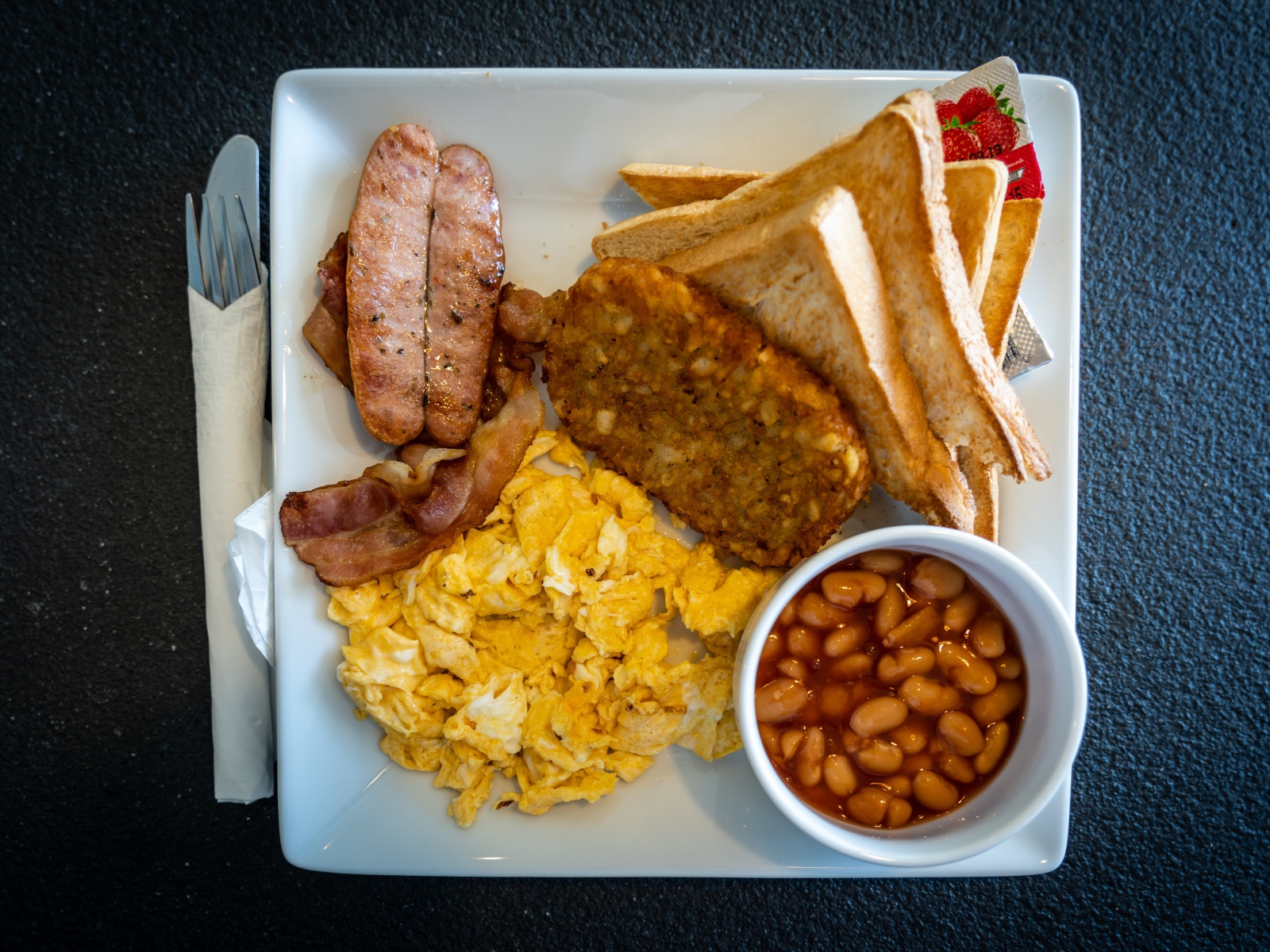 Завтрак на белой тарелке на черном столе 