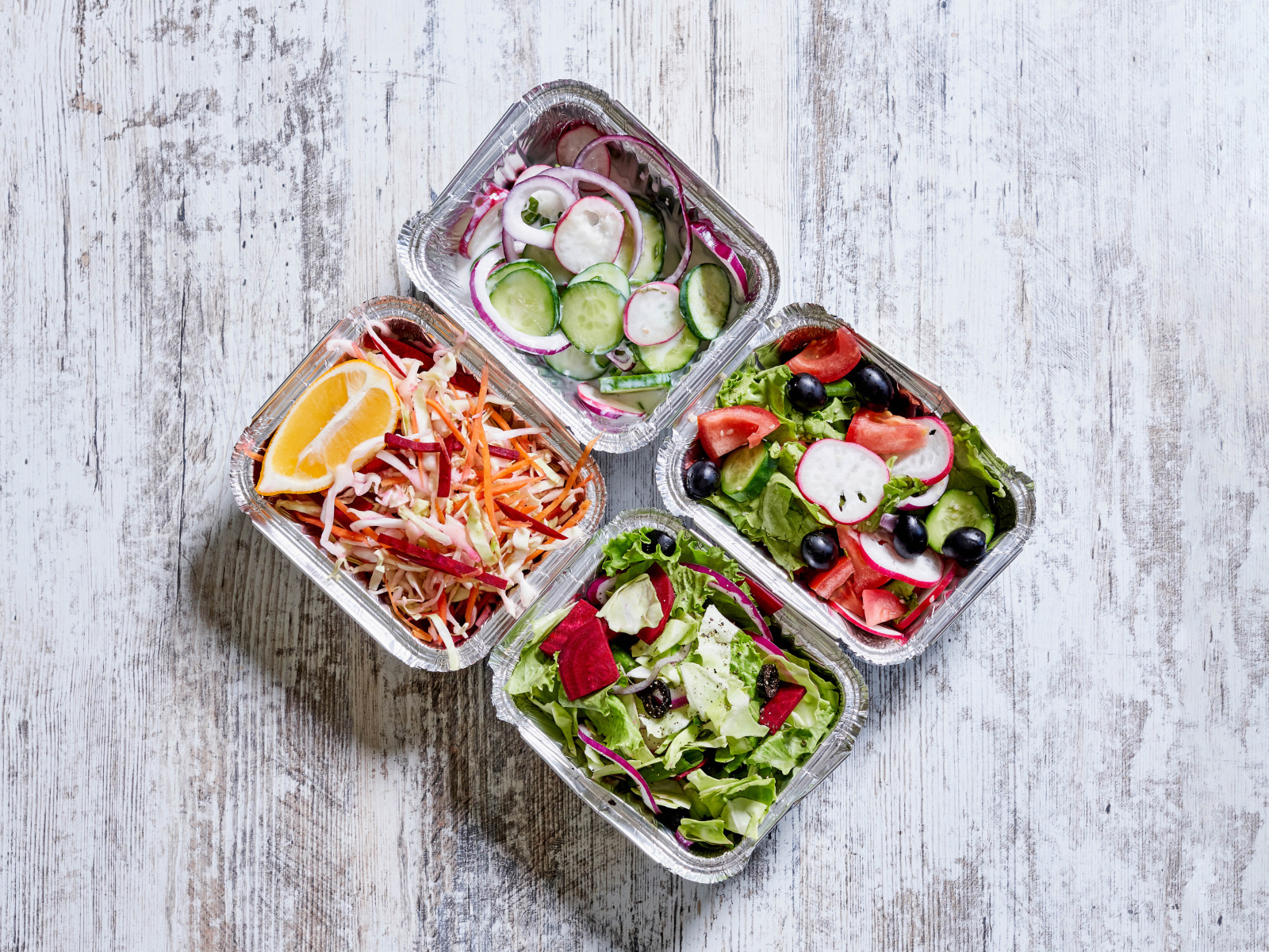 Разные овощные салаты в тарелках на сером столе 