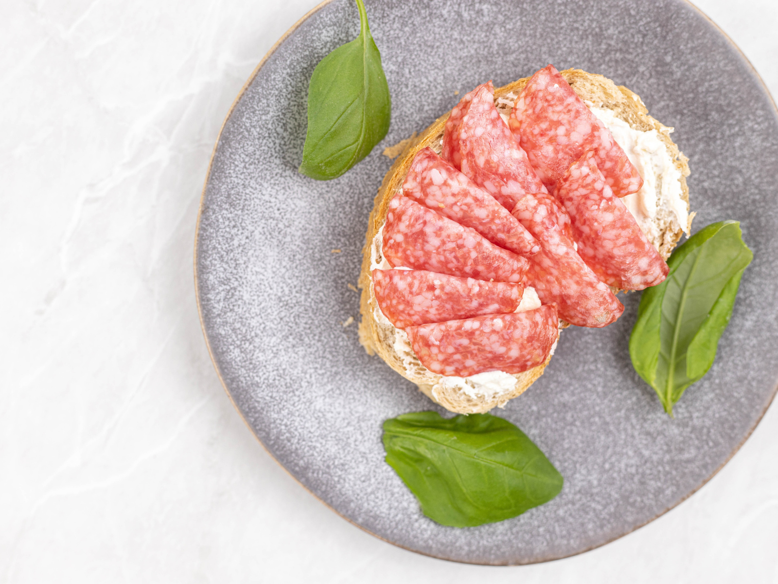 Бутерброд с маслом и колбасой на тарелке