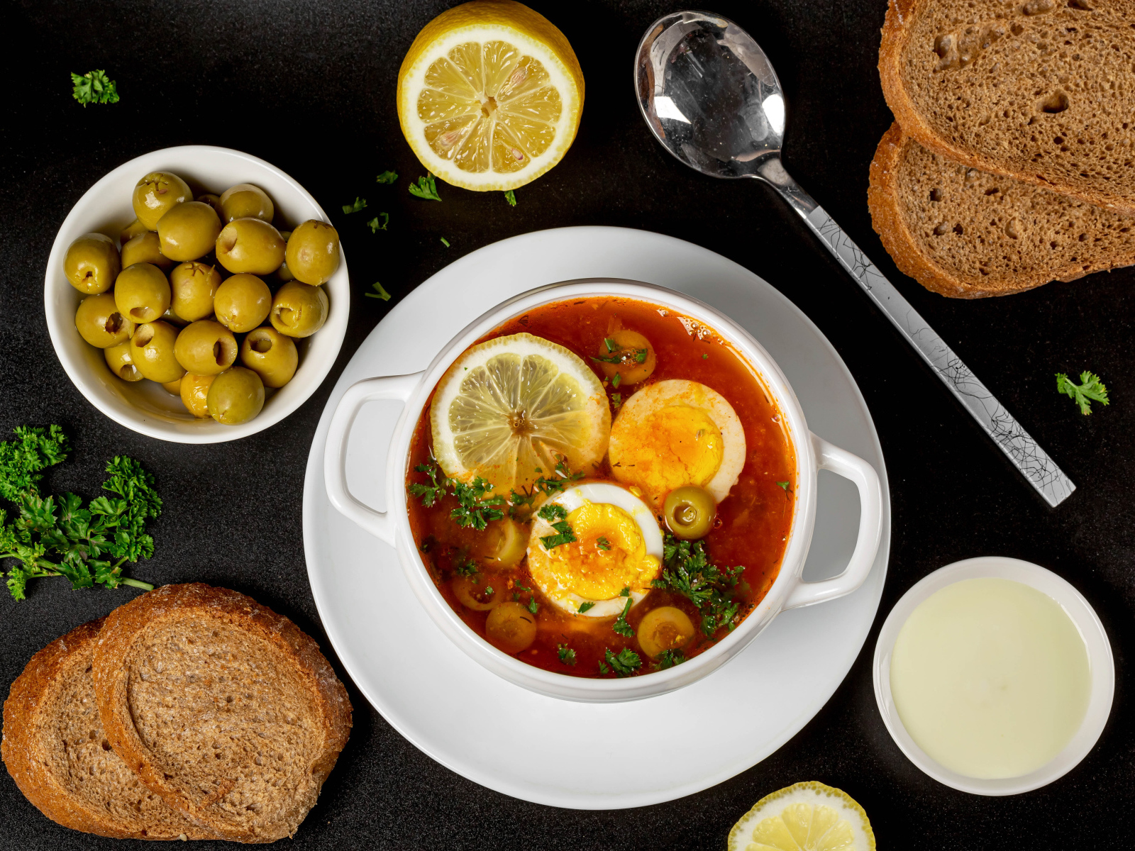 Солянка на столе  с хлебом и оливками 