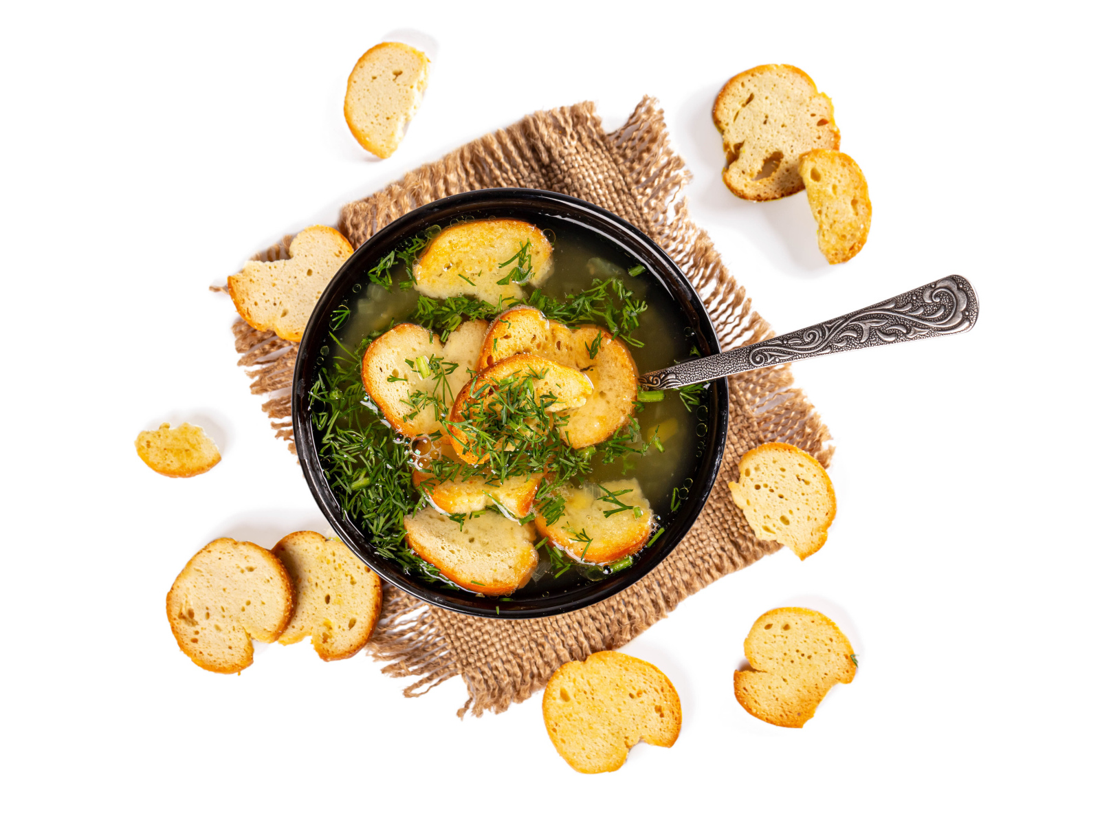 Суп с гренками и зеленью на столе на белом фоне